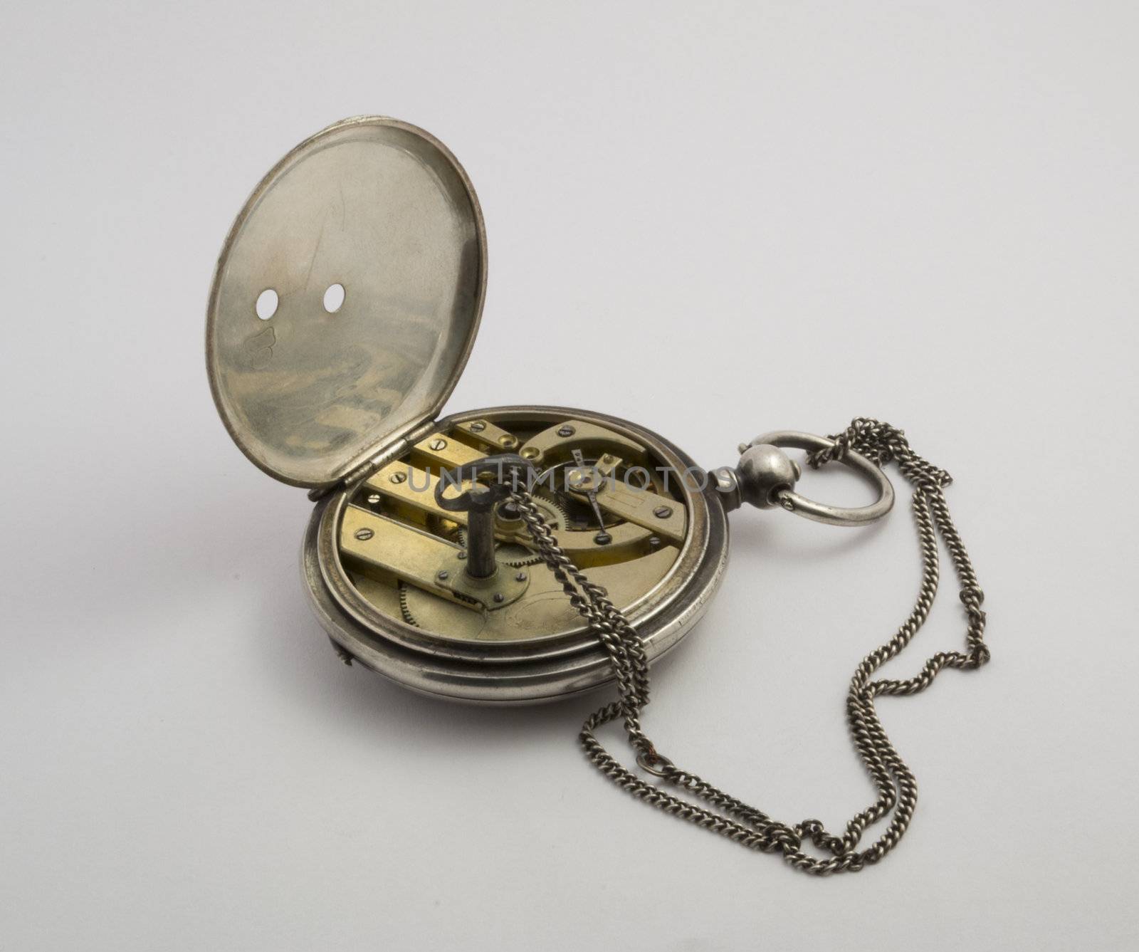 Antique pocket watch in silver with small key on a light background. Appearance with the clockwork.