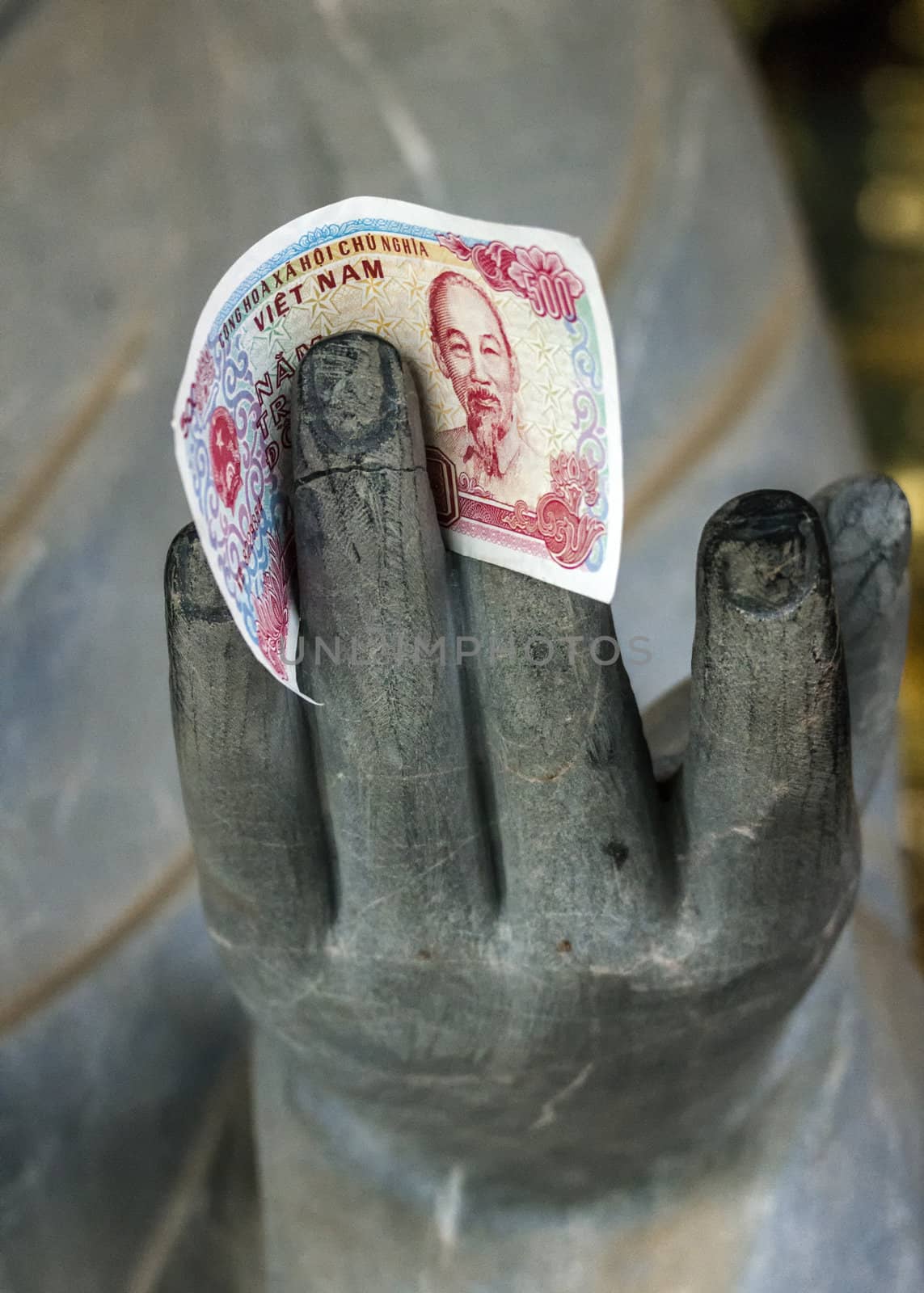 One colorful Dong note held by granite hand.