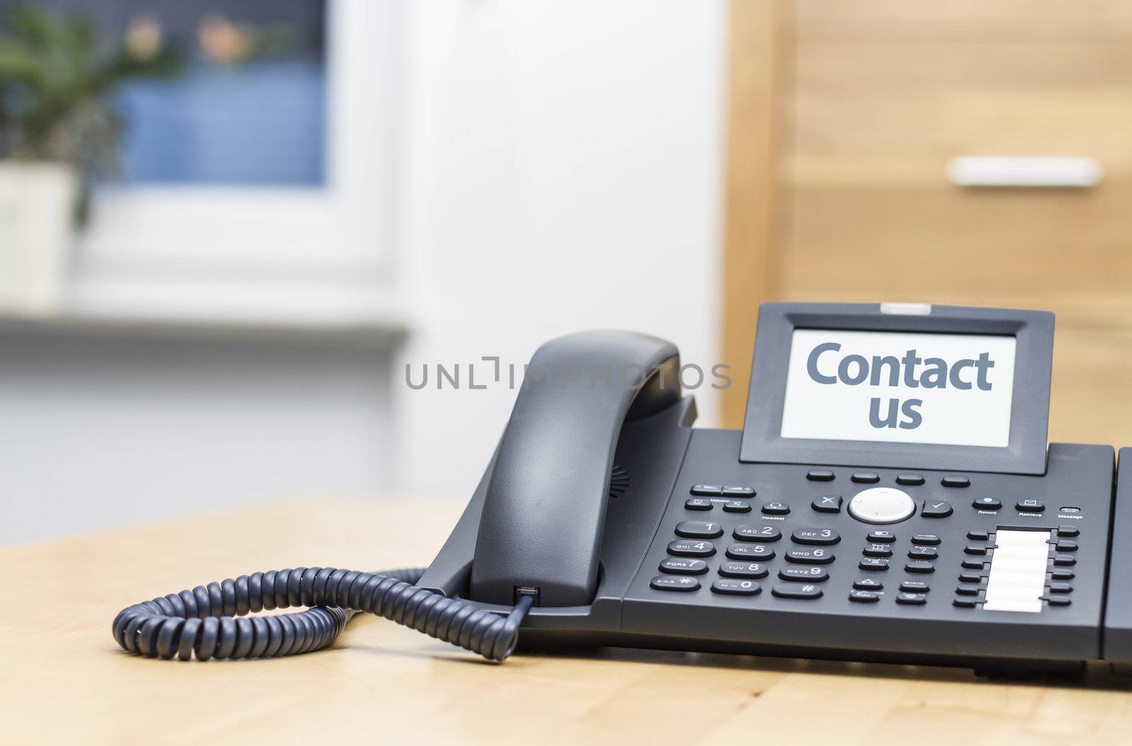 modern voip telephone on wooden desk saying CONTACT US