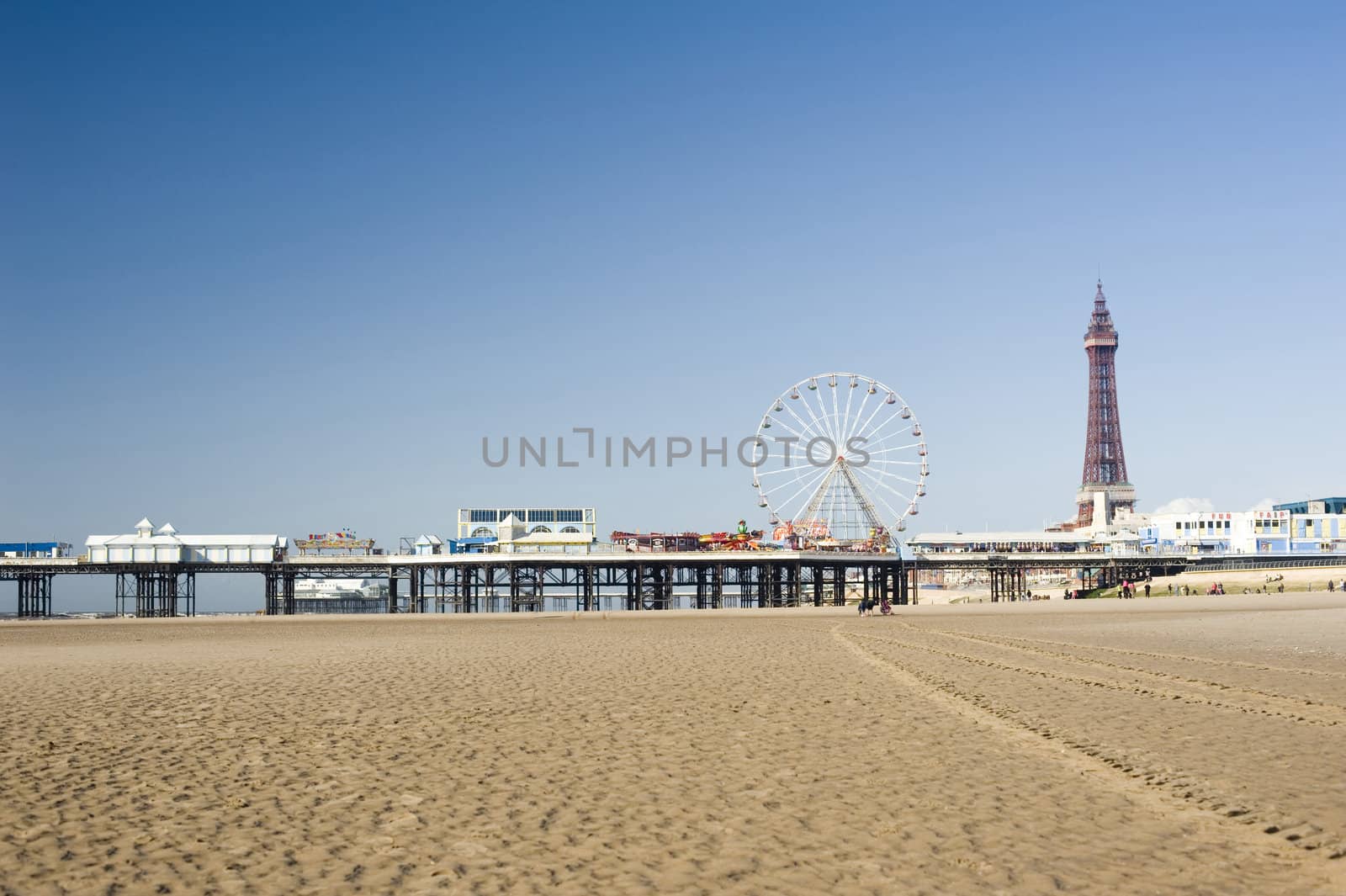 View across the sand of Blackpool Beach to the pier with the historic Blackpool Tower and pier in the background