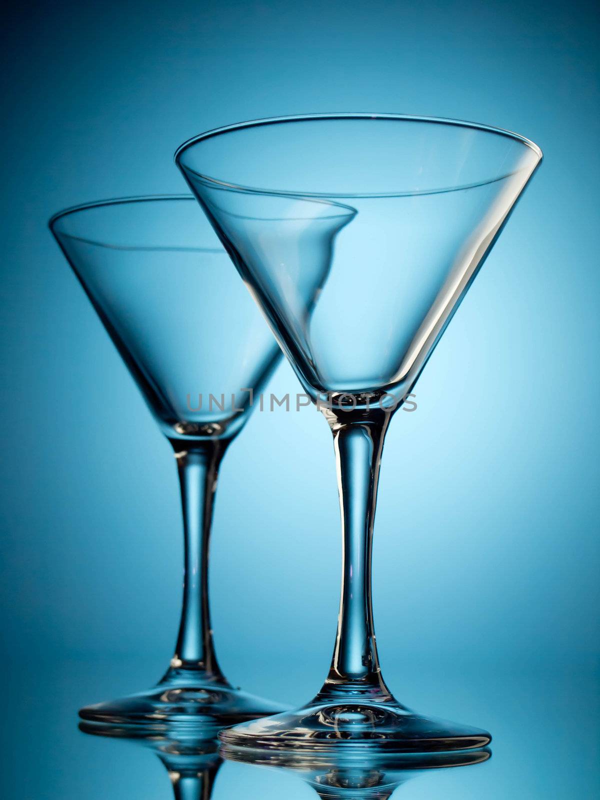 Two empty martini glasses on blue background