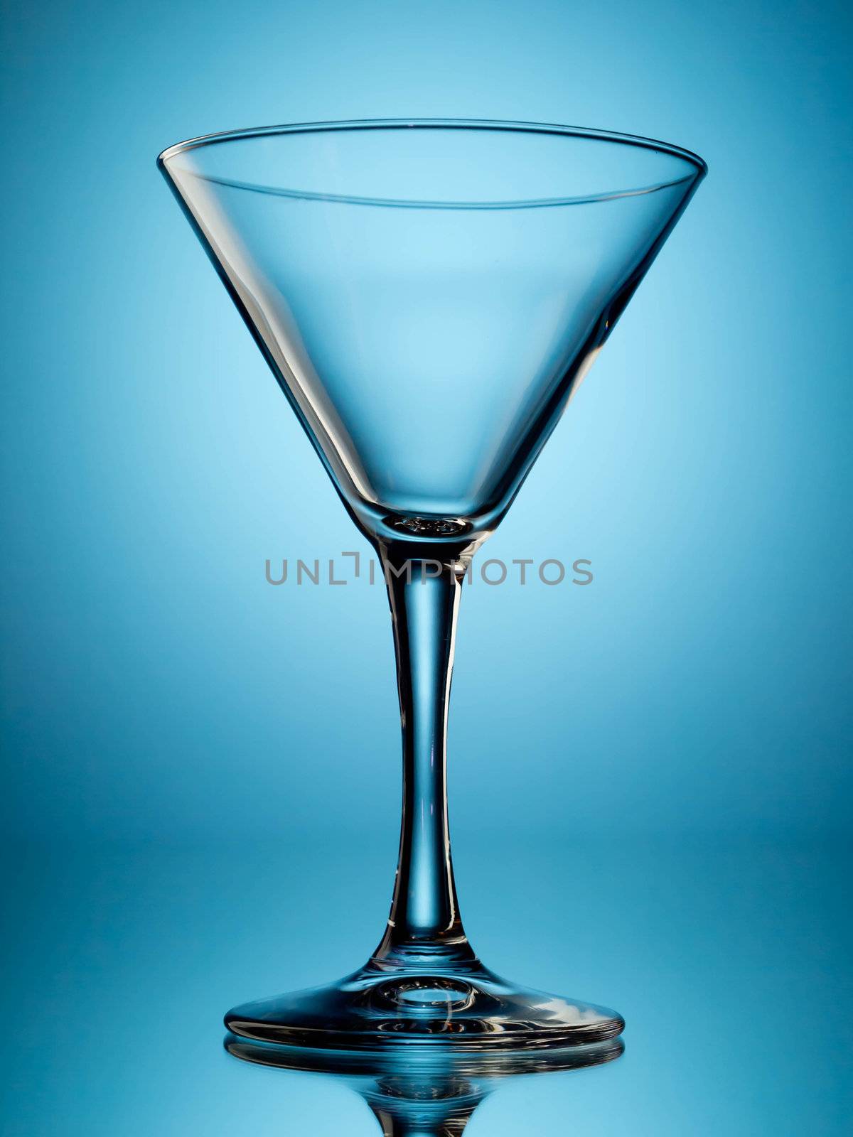 One empty martini glass on blue background
