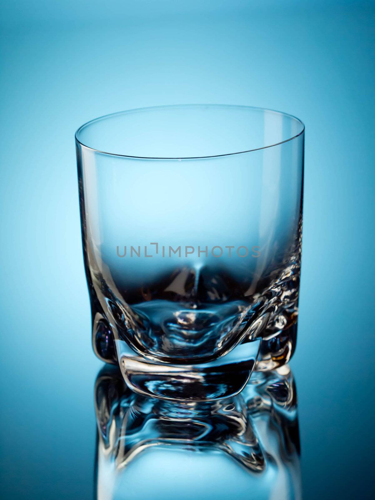 One empty tumbler glass on blue background