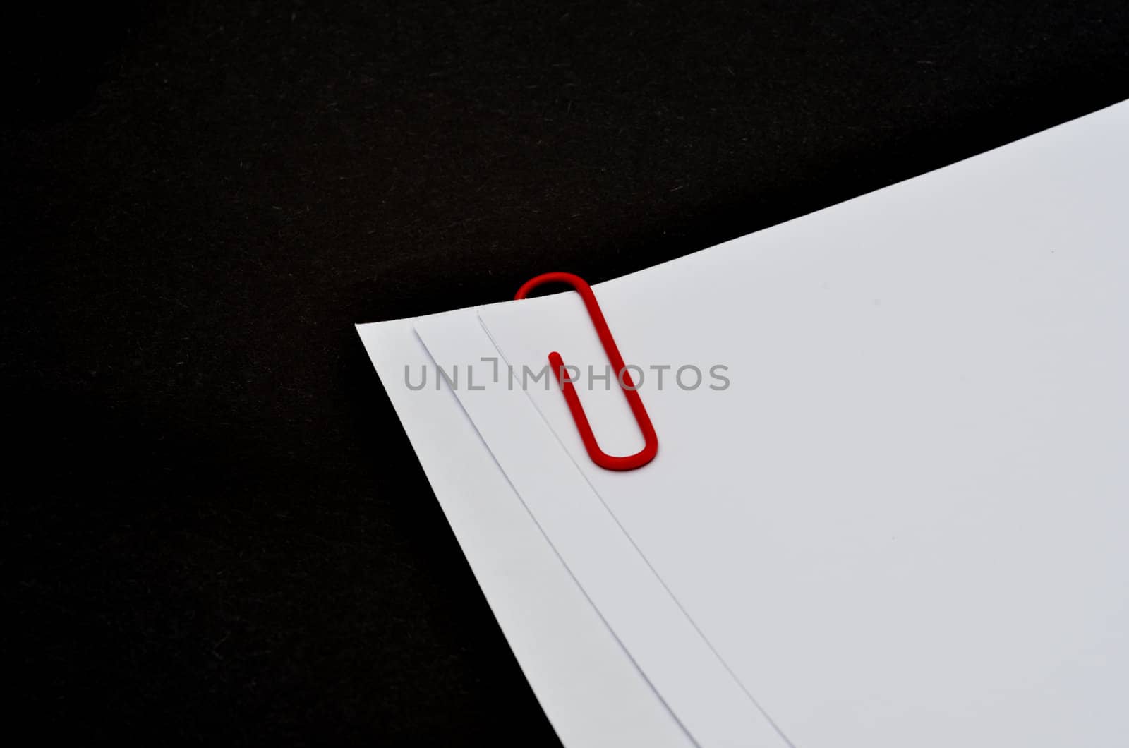 Paper clip on white paper with black background