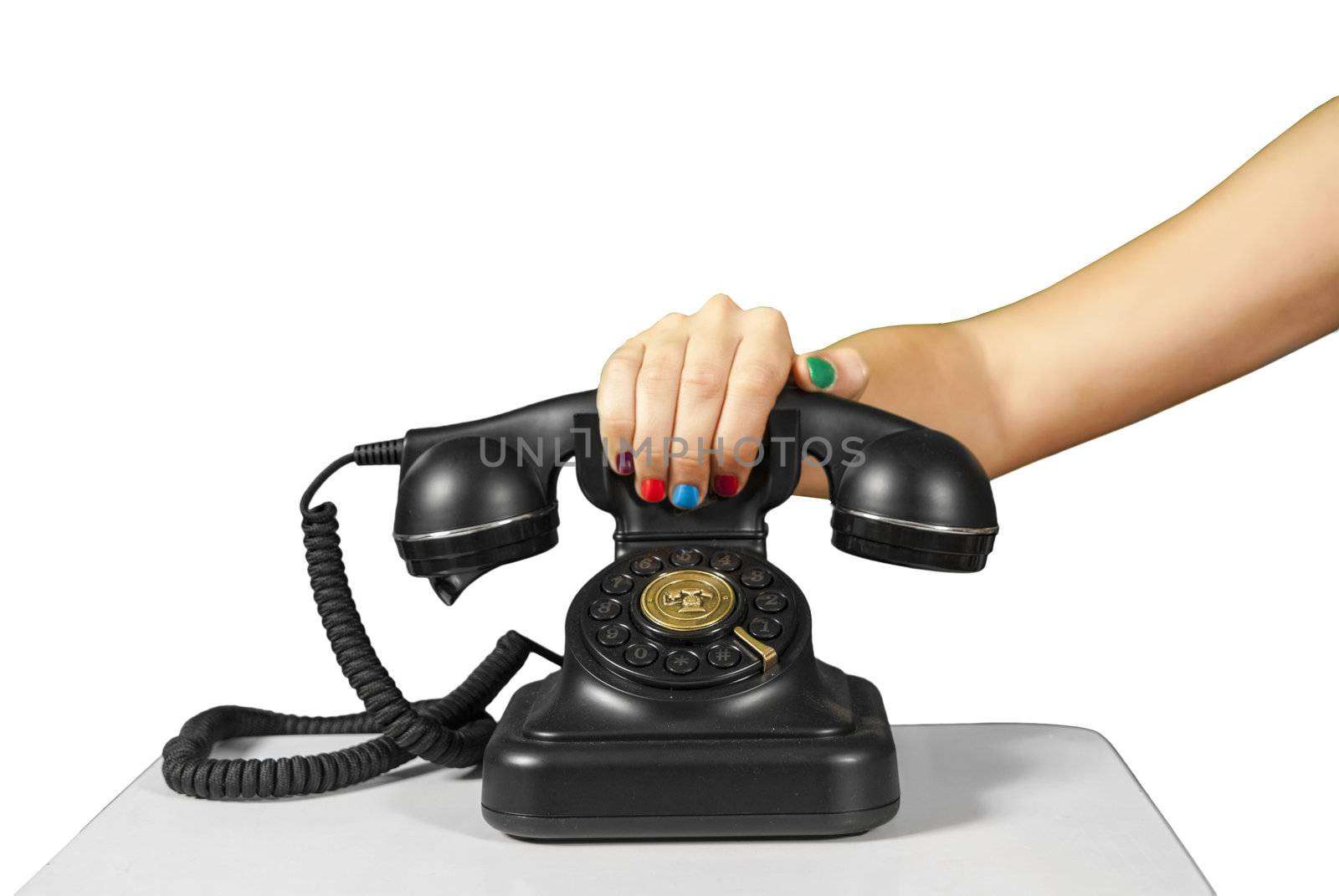 A hand holding the handset of an old black vintage rotary style telephone isolated over white.