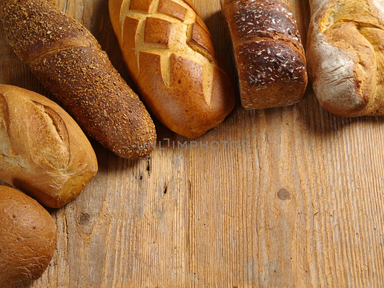 Photo of loaves of uncut bread resting on an old wood table.
