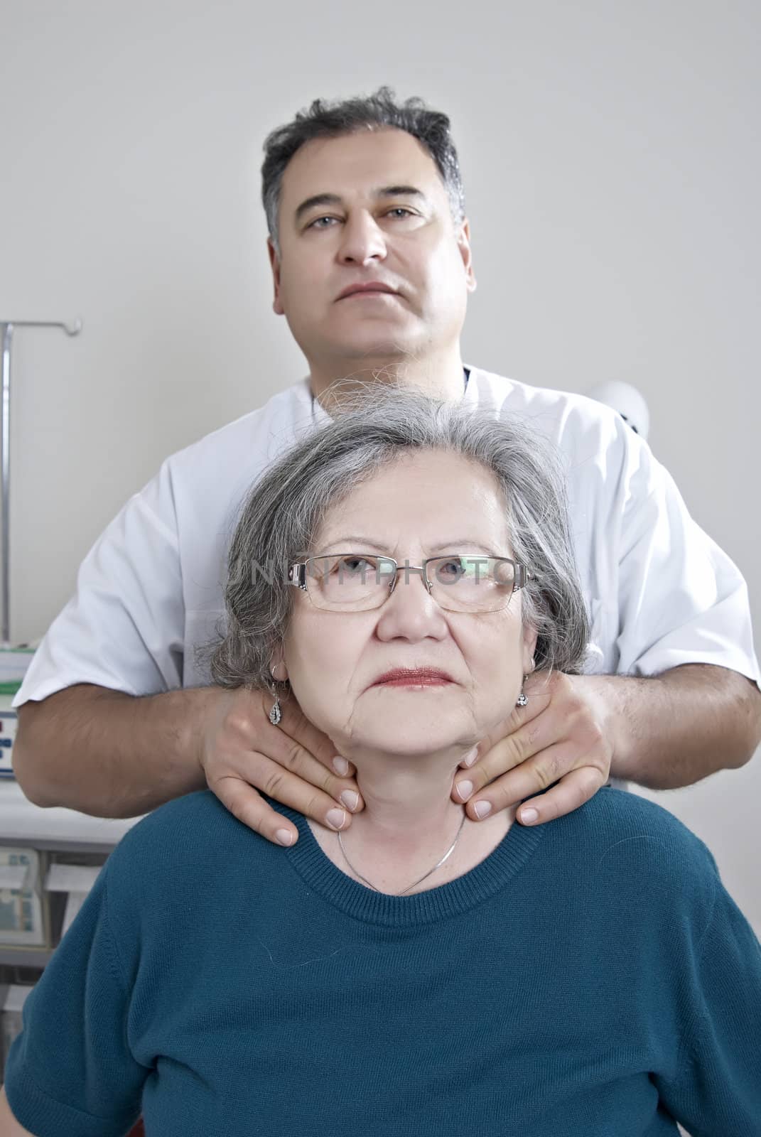 Doctor examing thyroid of mature patient