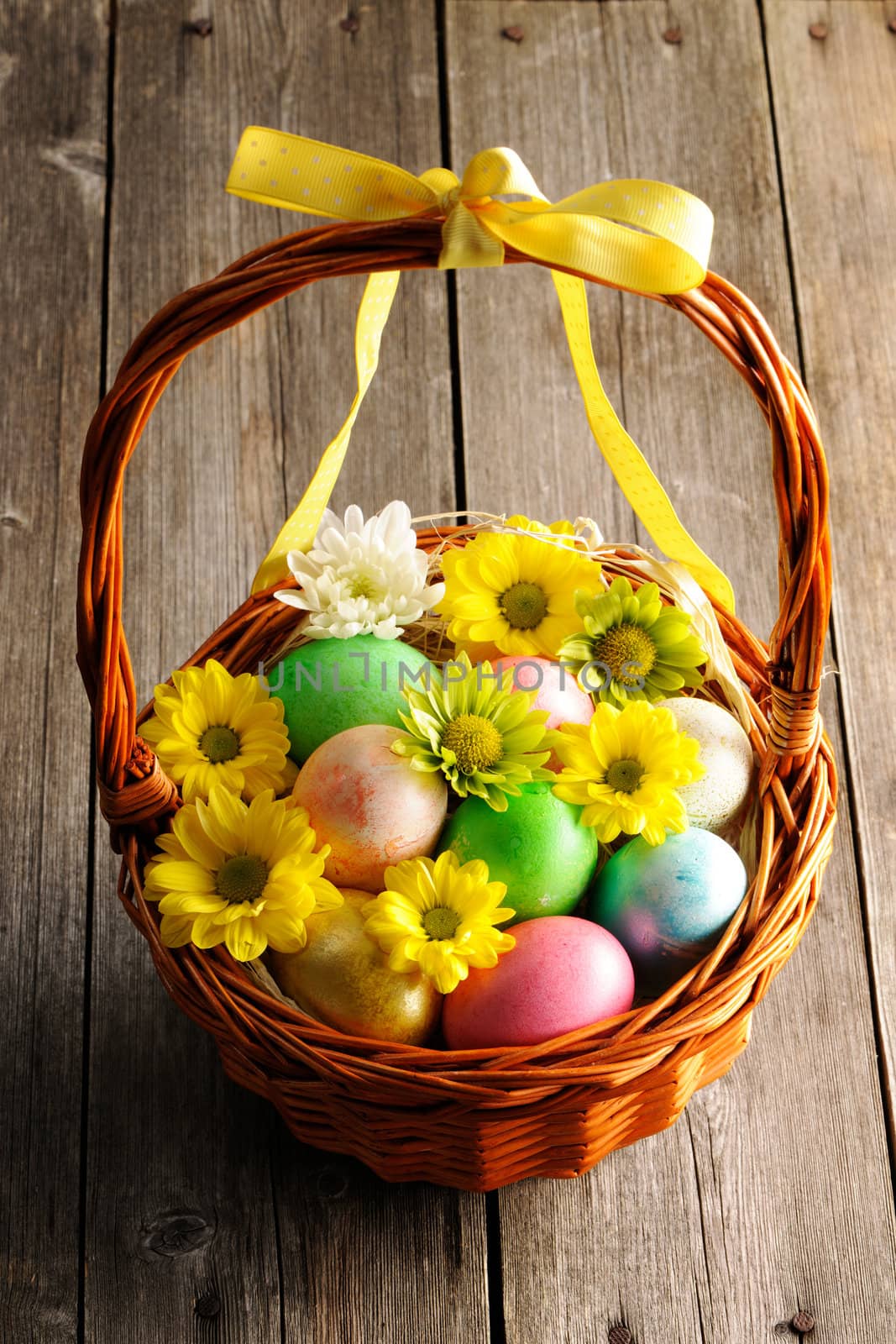 Colored easter eggs in basket on wooden table