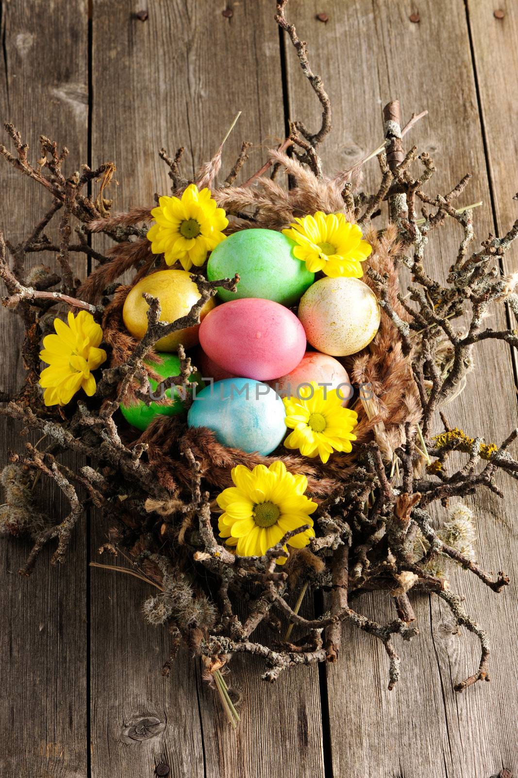 Colored easter eggs in nest on wooden table