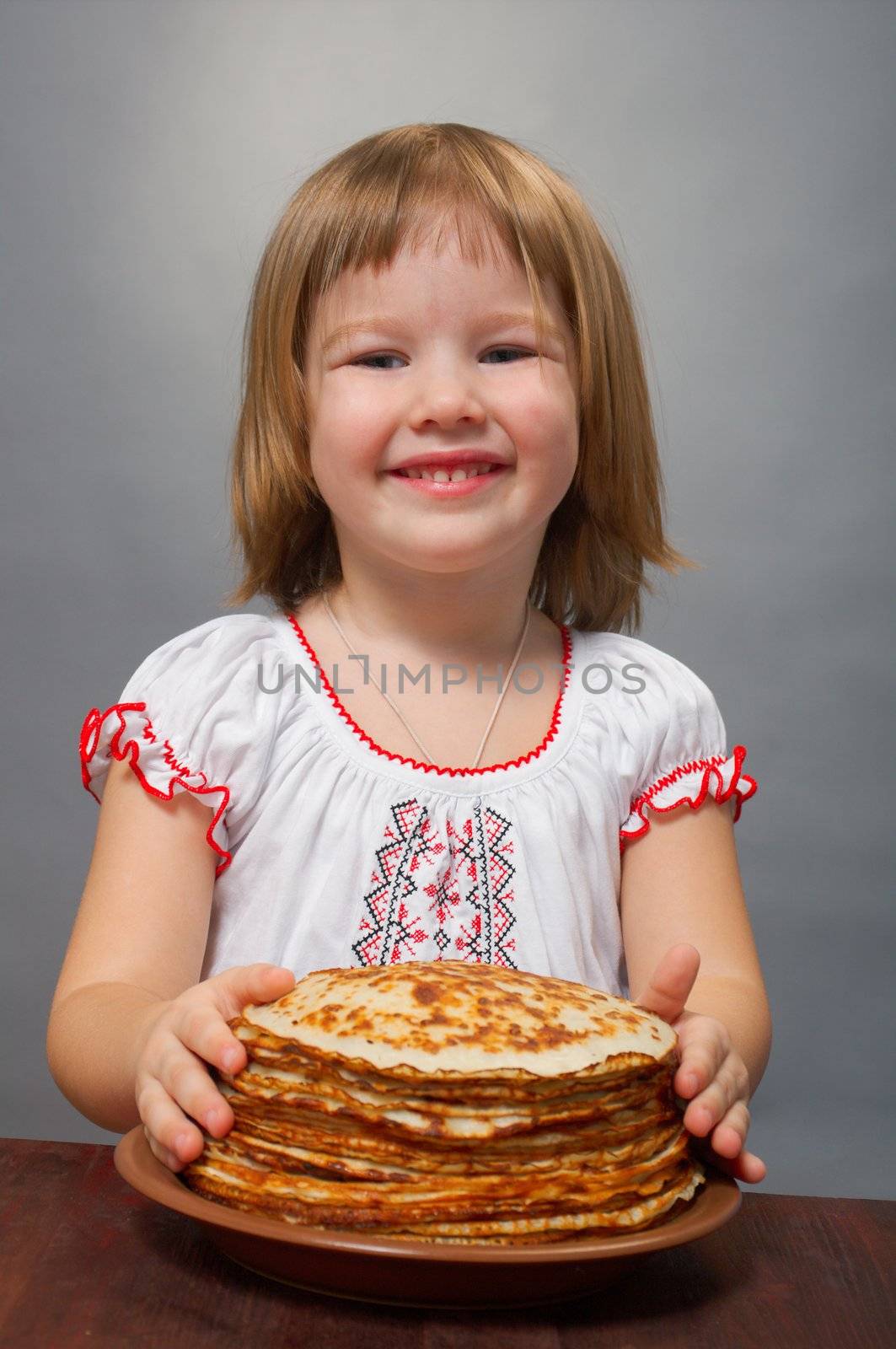 Russian little girl eats pancakes with red caviar.