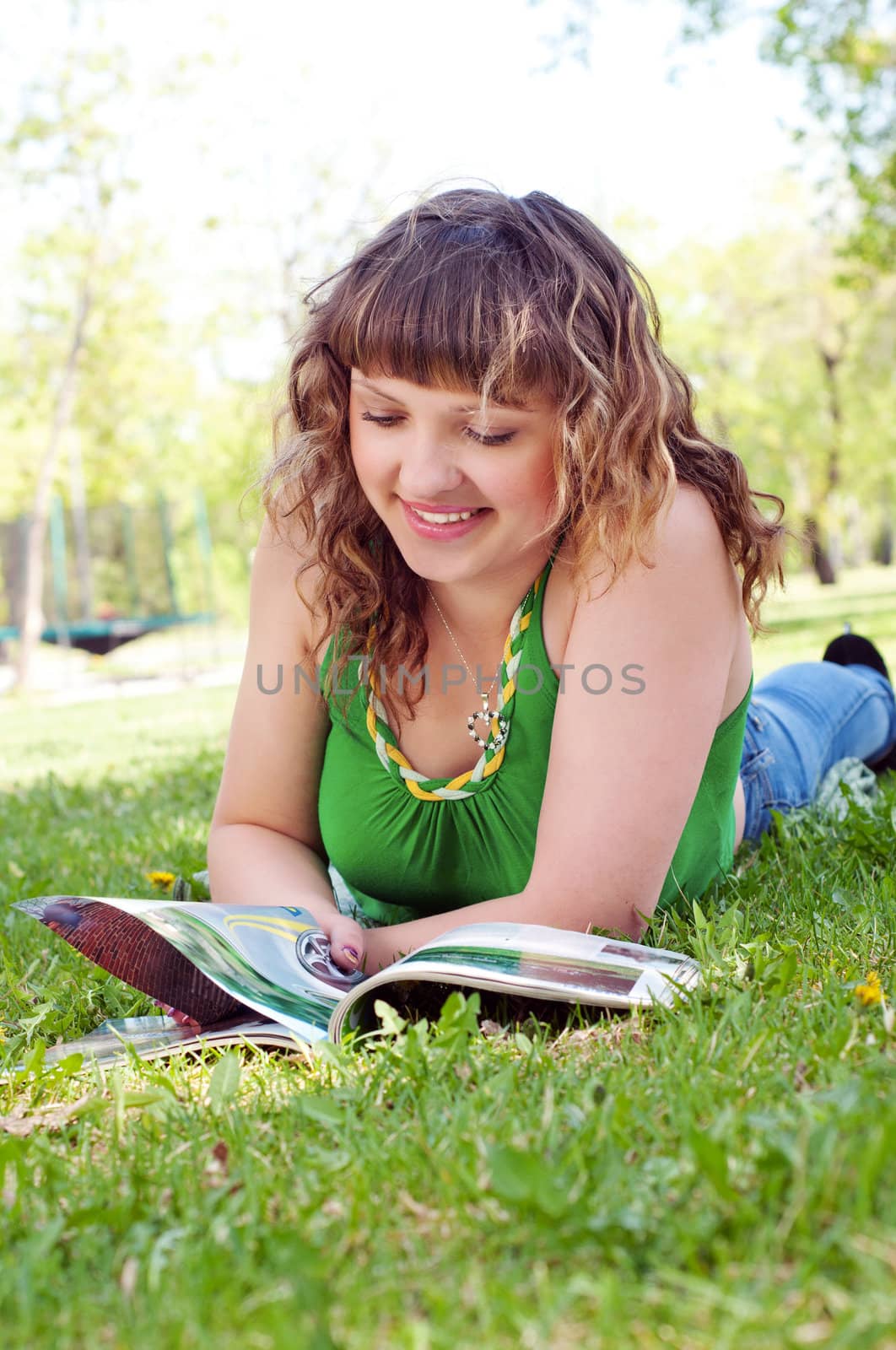 portrait of a young woman in a park reading a magazine