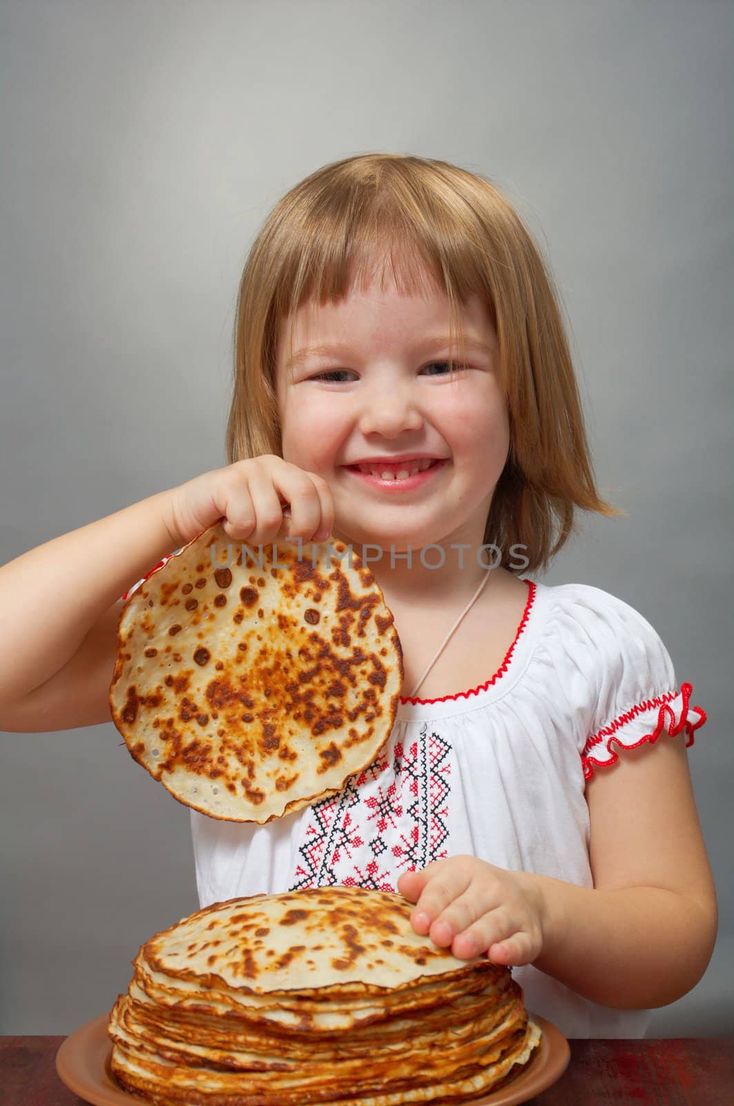 Russian little girl eats pancakes with red caviar.