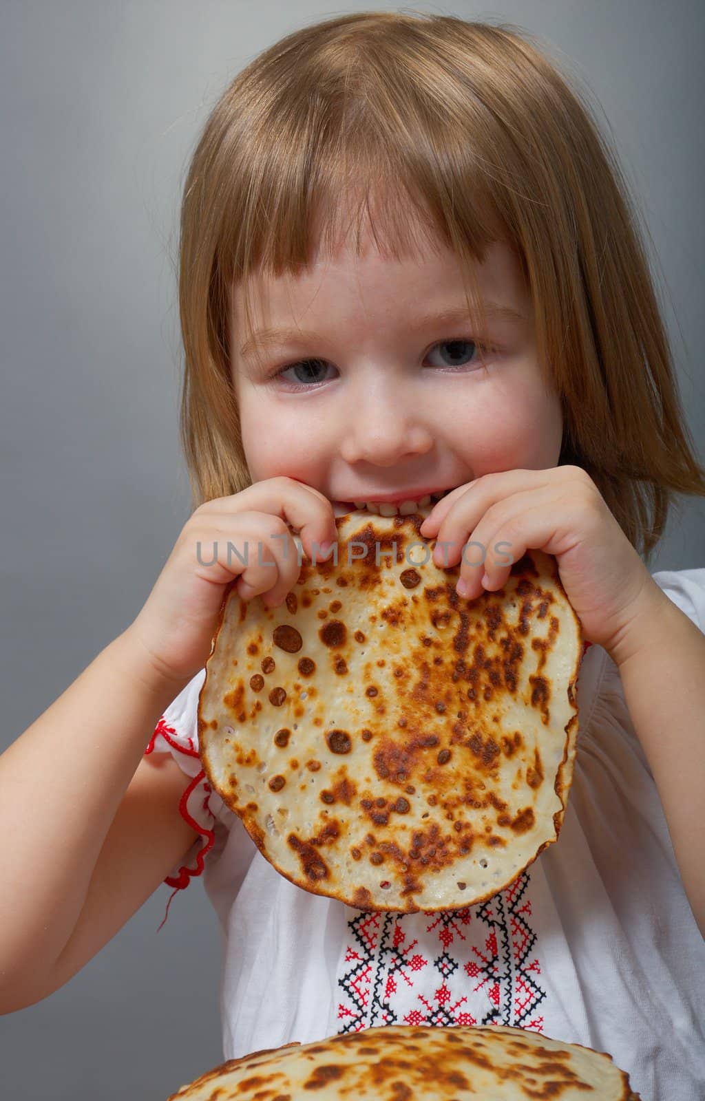 Russian little girl eats pancakes with red caviar.