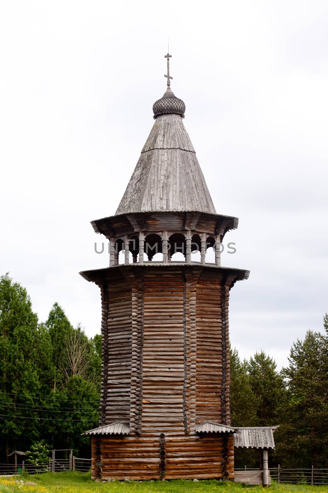 A traditional wooden russian bell-tower in a forest

