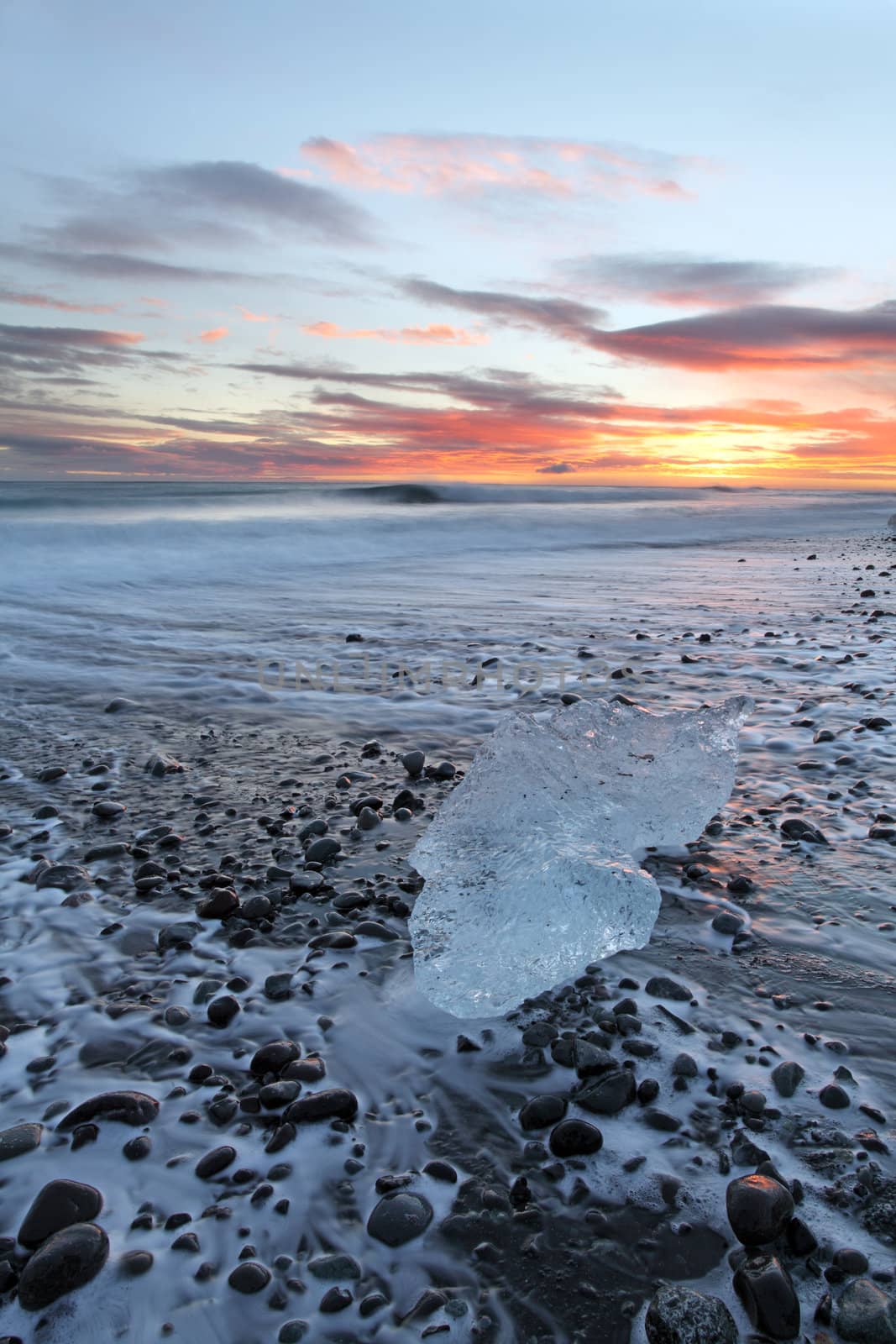 Iceburg on vocanic black sand beach at sunset in south Iceland