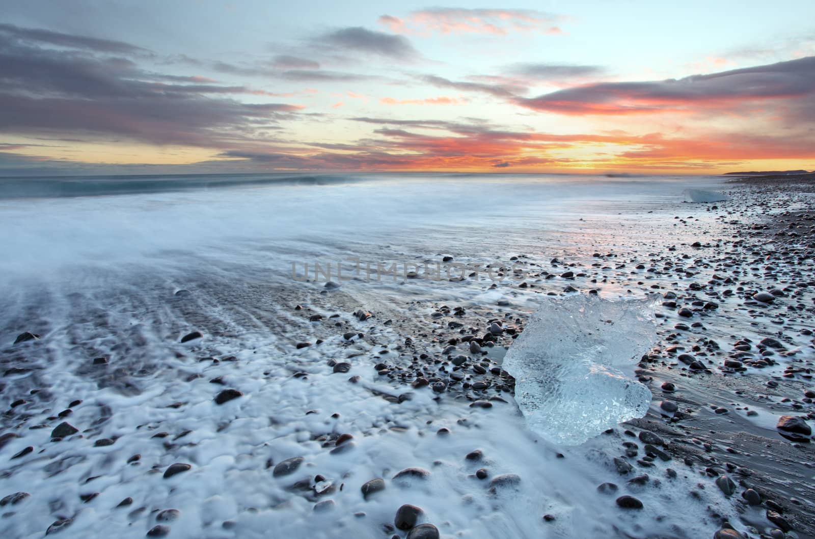 Iceburg on vocanic black sand beach at sunset in south Iceland