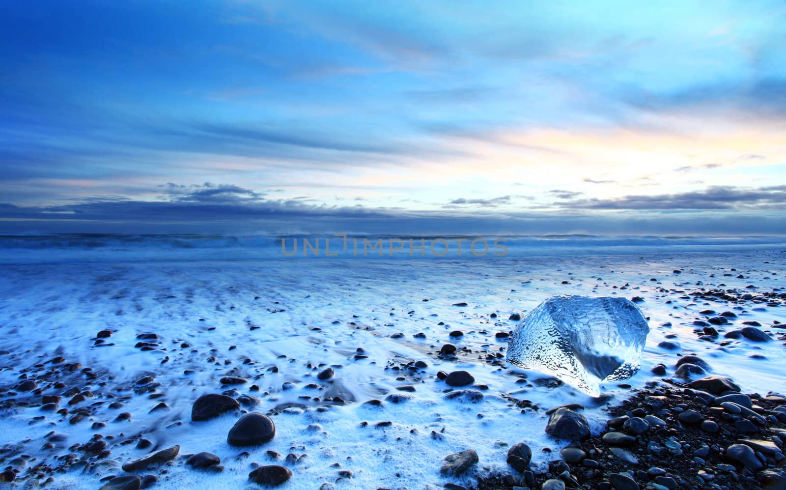 Iceburg on vocanic black sand beach at sunset in south Iceland