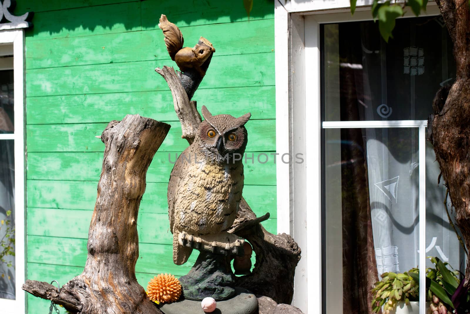 Wooden owl and squrrel in front of a cottage
