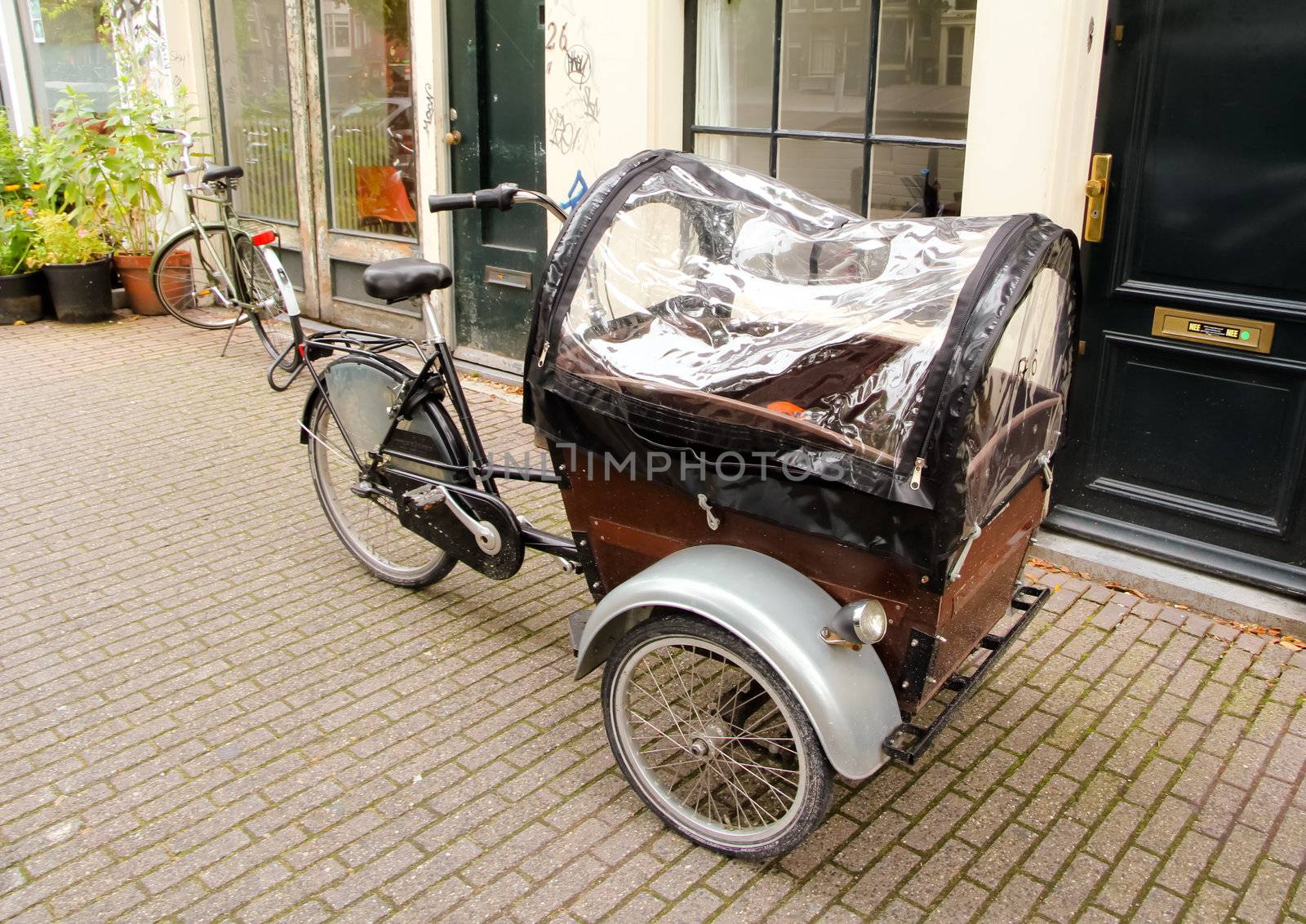Three wheels black retro bicycle with wooden casing cover on a street of Amsterdam.
