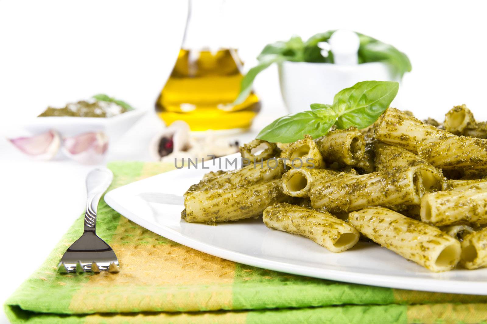 Pasta with pesto sauce and ingredients over white