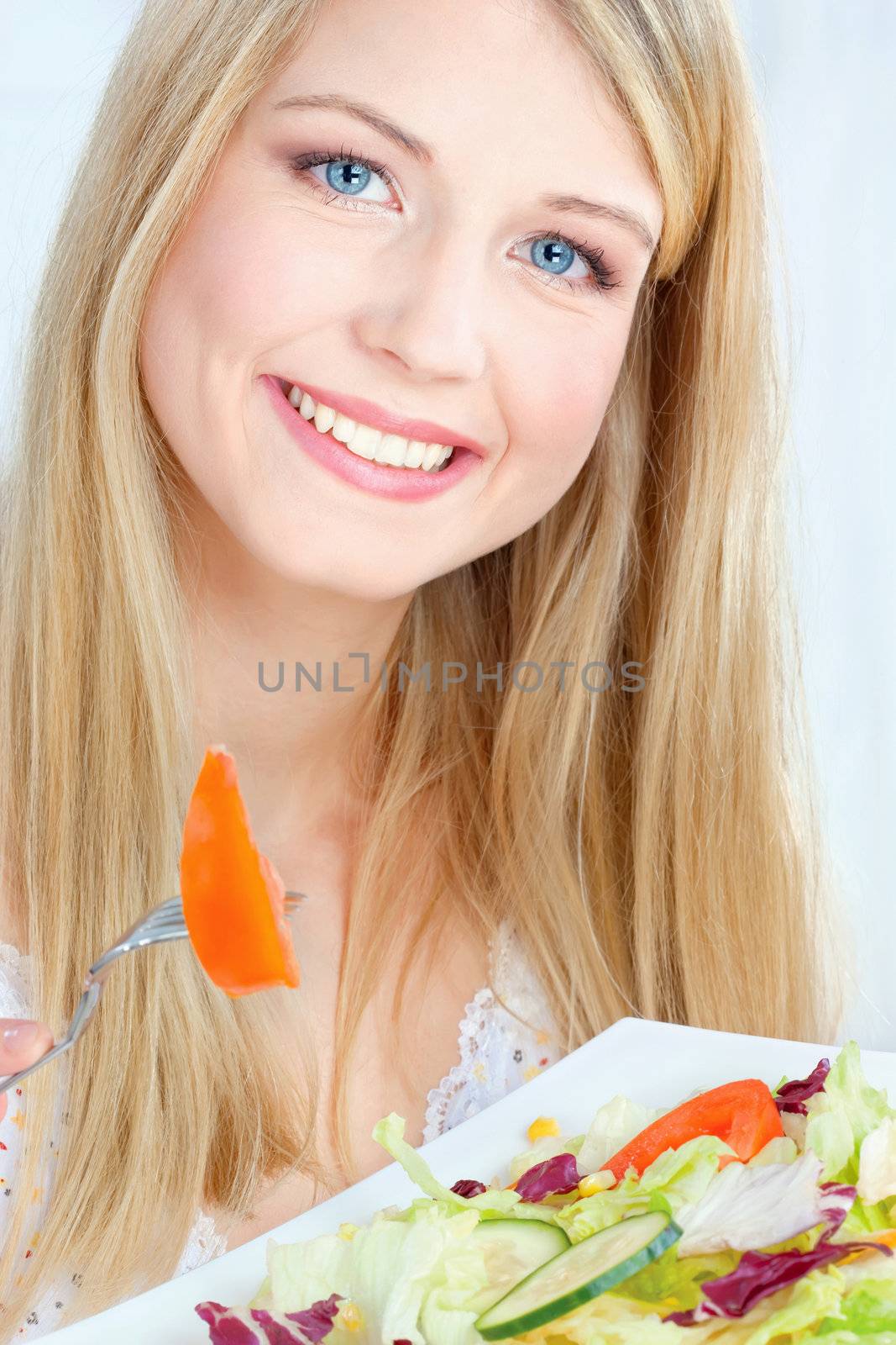 Blond happy woman eating salad