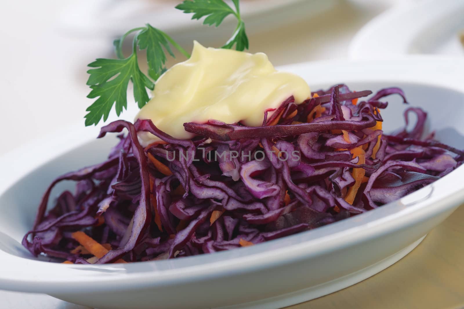 Close-up picture of a salad from red cabbage with mayonnaise and parsley.