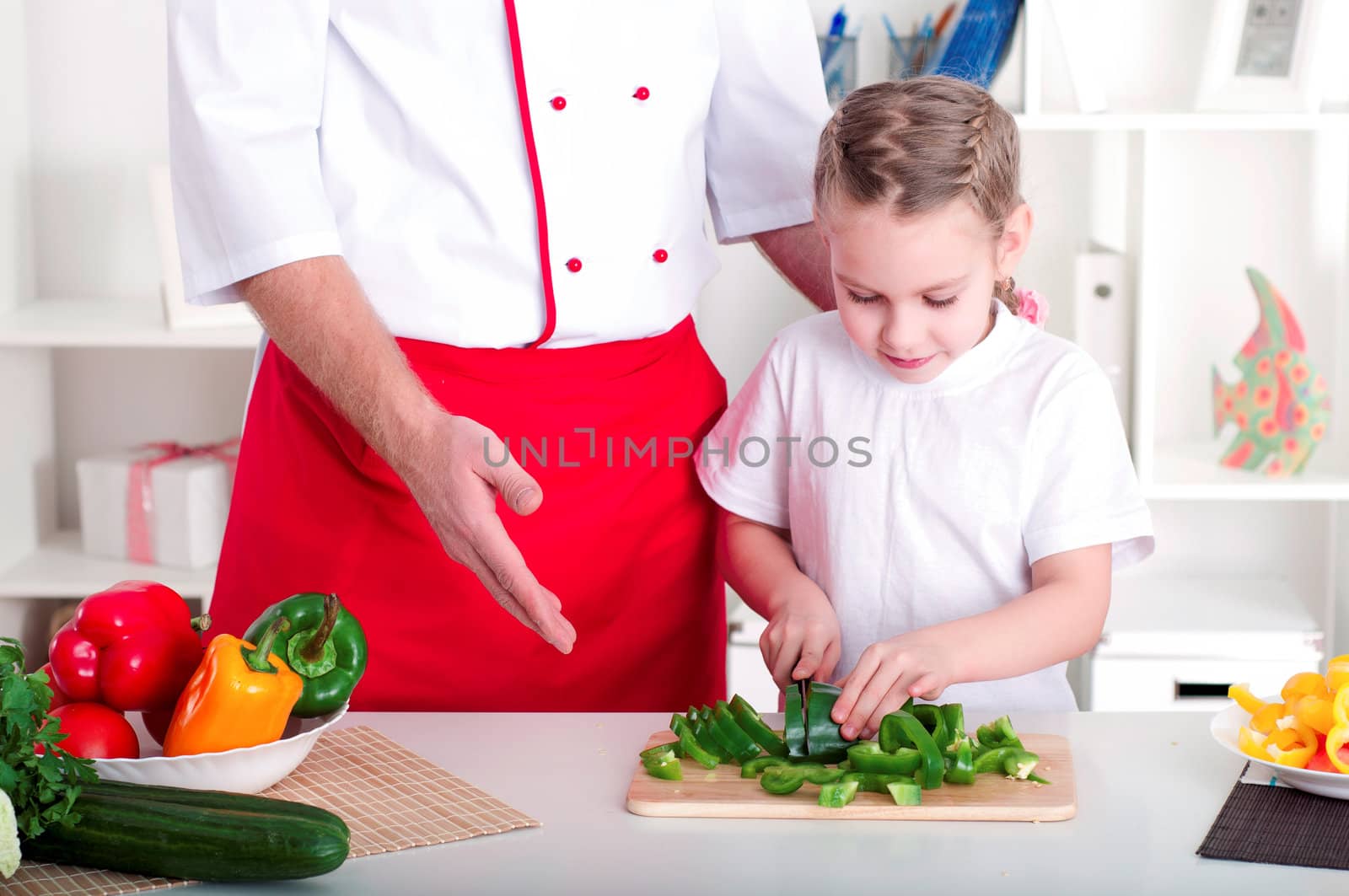 portrait of father and daughter cooking salad together in the kitchen
