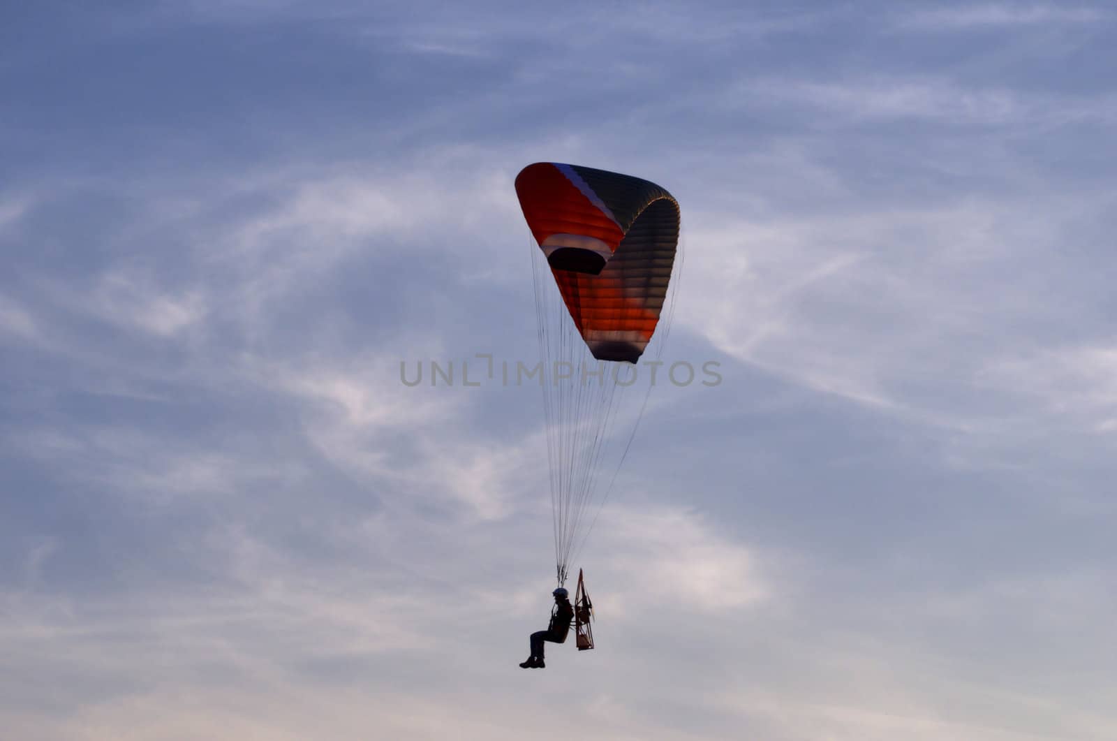 Photo shows a paraglider flies on a background of blue sky.