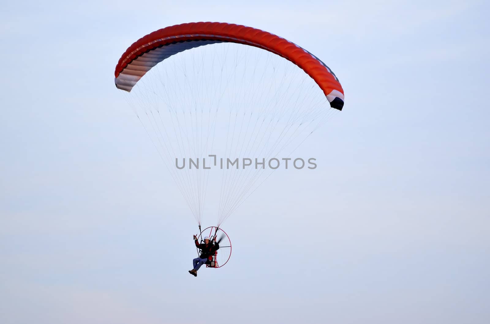 Photo shows a paraglider flies on a background of blue sky.