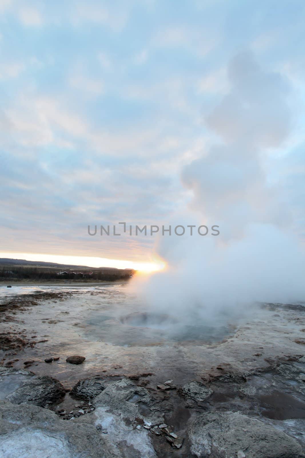 Strokkur Geyser in Iceland erupting at sunset in winter
