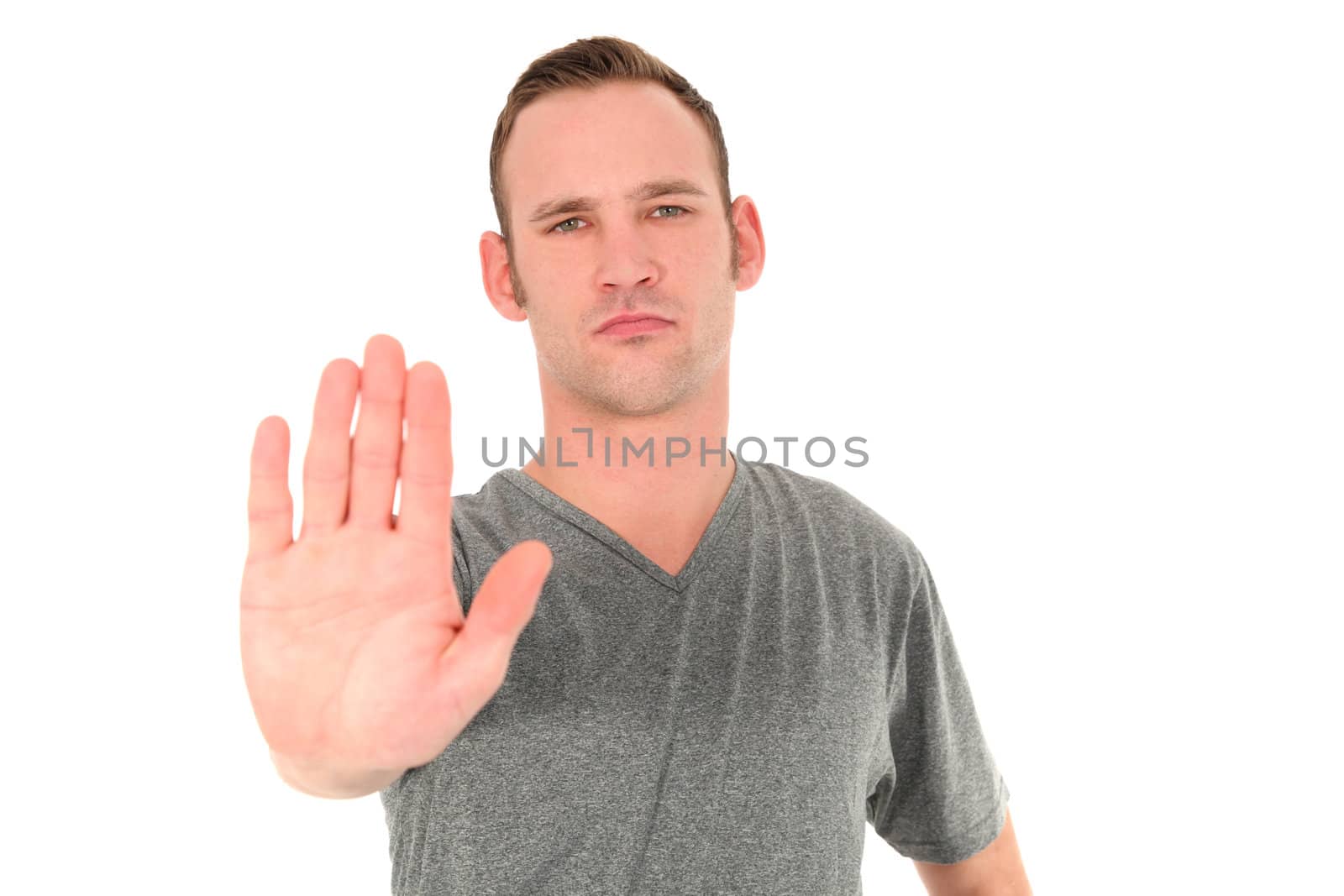 Young man making a Stop gesture holding up the flat of his palm with a determined expression on his face isolated on white