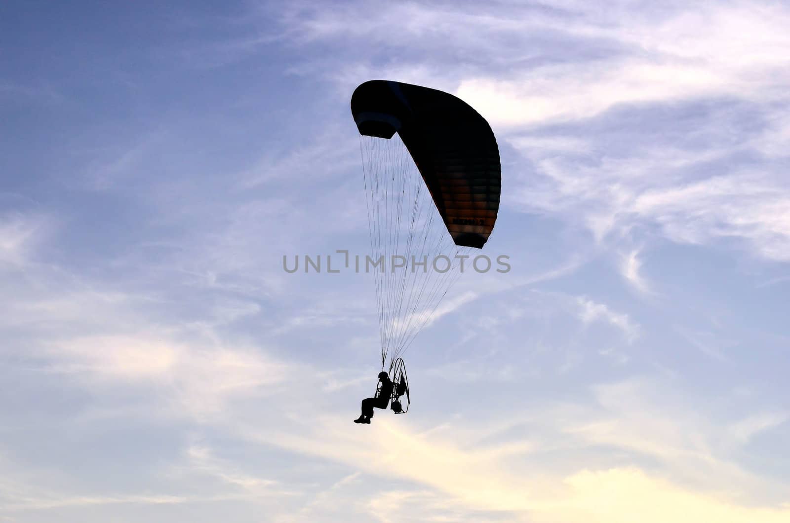 Photo shows a paraglider flies on a background of blue sky.