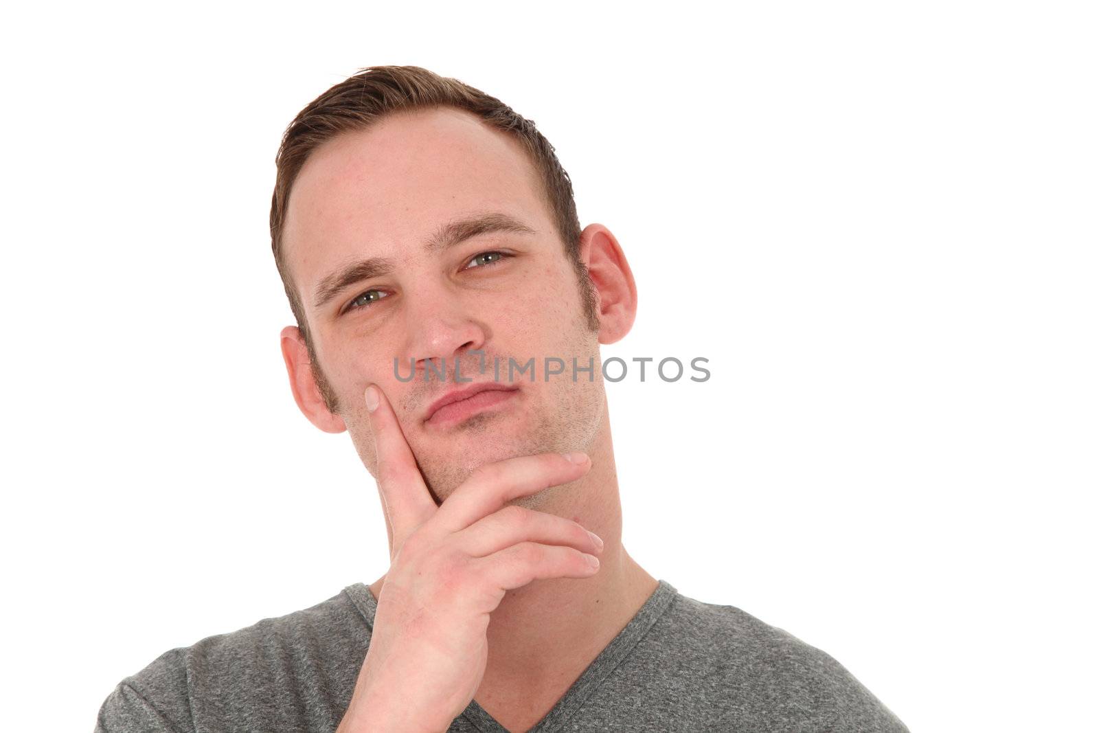 Pensive attractive young man standing thinking with his hand to his chin and a faraway look in his eyes isolated on white