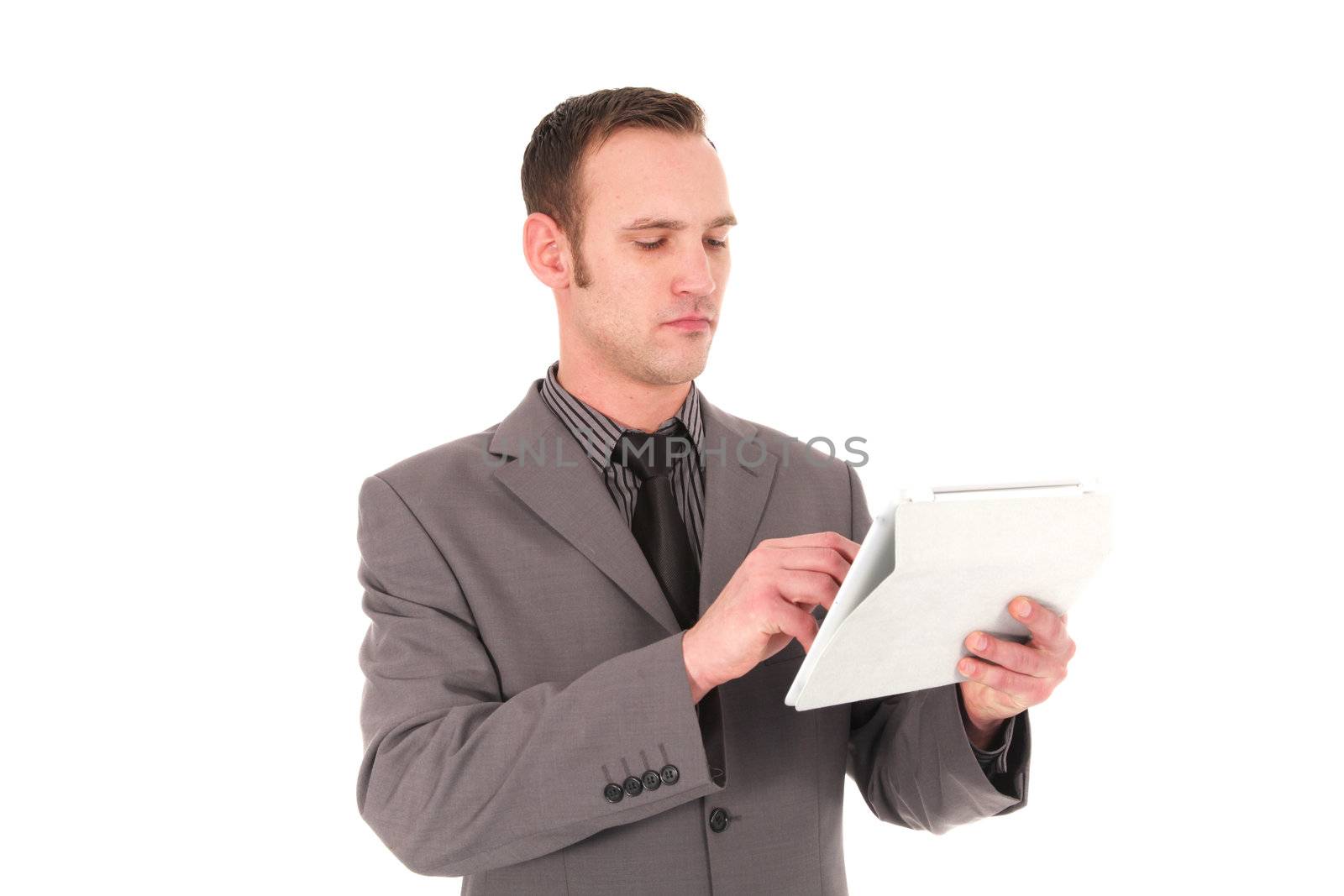 Attractive young businesman standing working on a handheld tablet touching the screen with his finger isolated on white Portrait of a young business man working on his tablet.