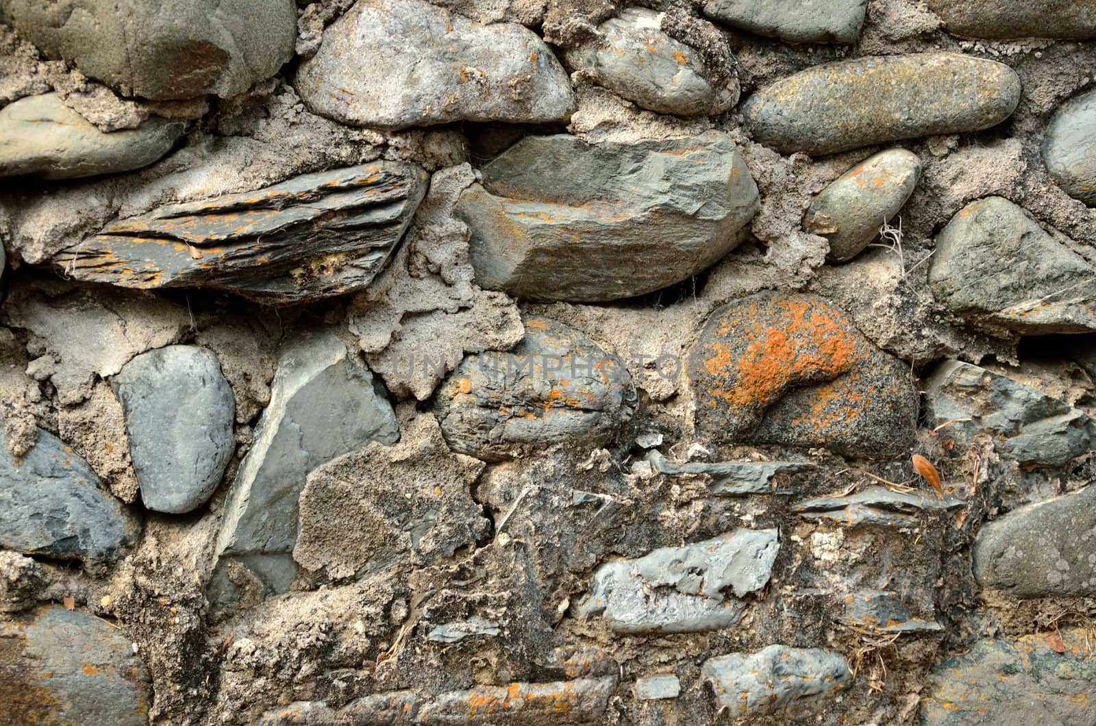 Old masonry wall of uneven and varying size rocks and stones