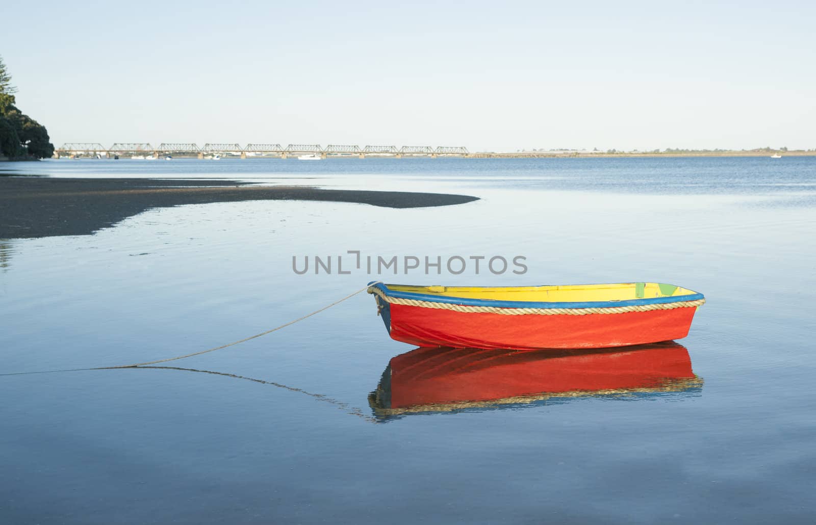 Small bright red boat floating on calm water.