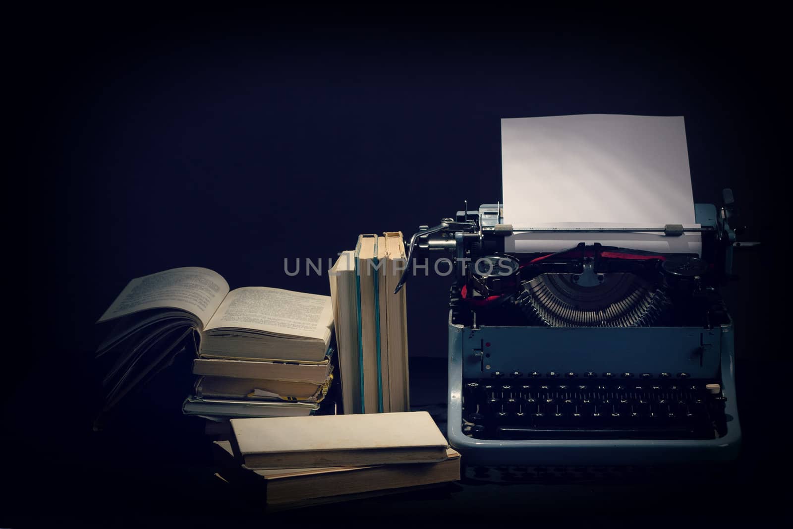 Old typewriter with opened books, retro colors with black background