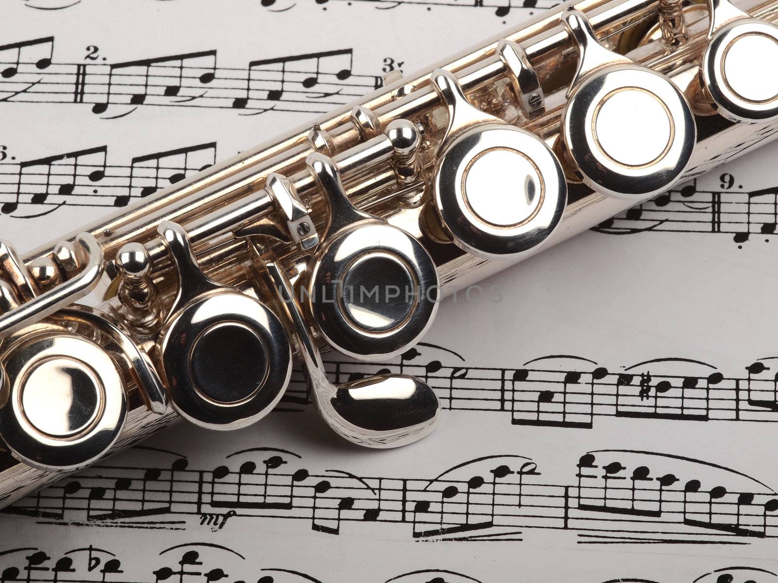 
A used flute rests across an open musical score. Only one line of music is in focus.