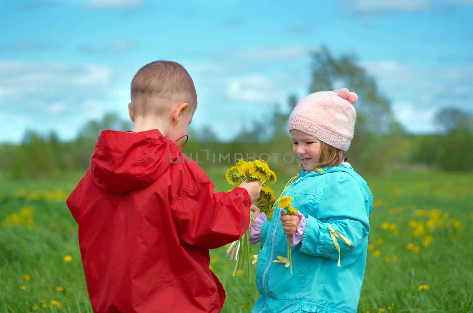 boy and small girl  on meadow with dandelion