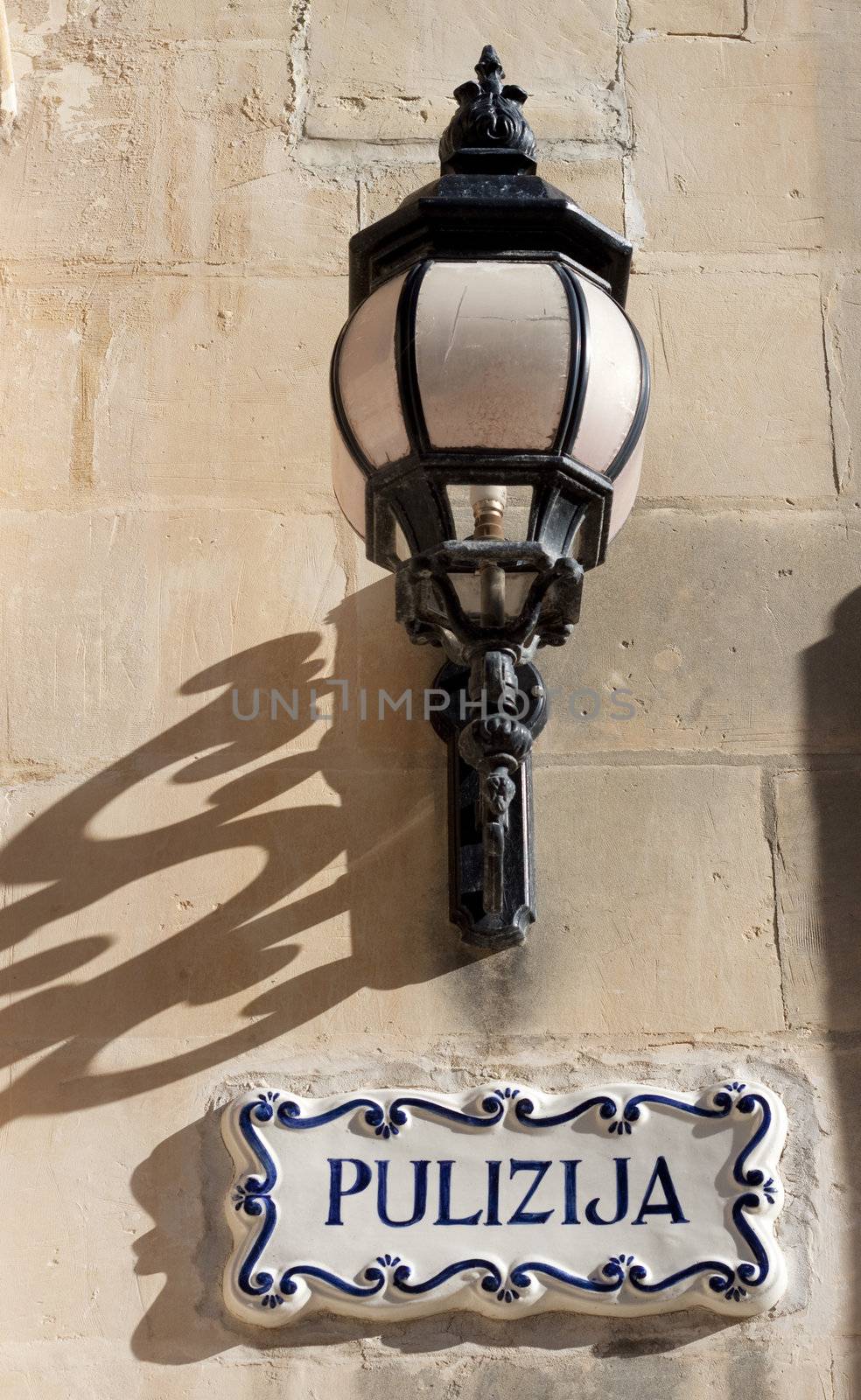 Closeup of a lamp and a sign for a police station in malta