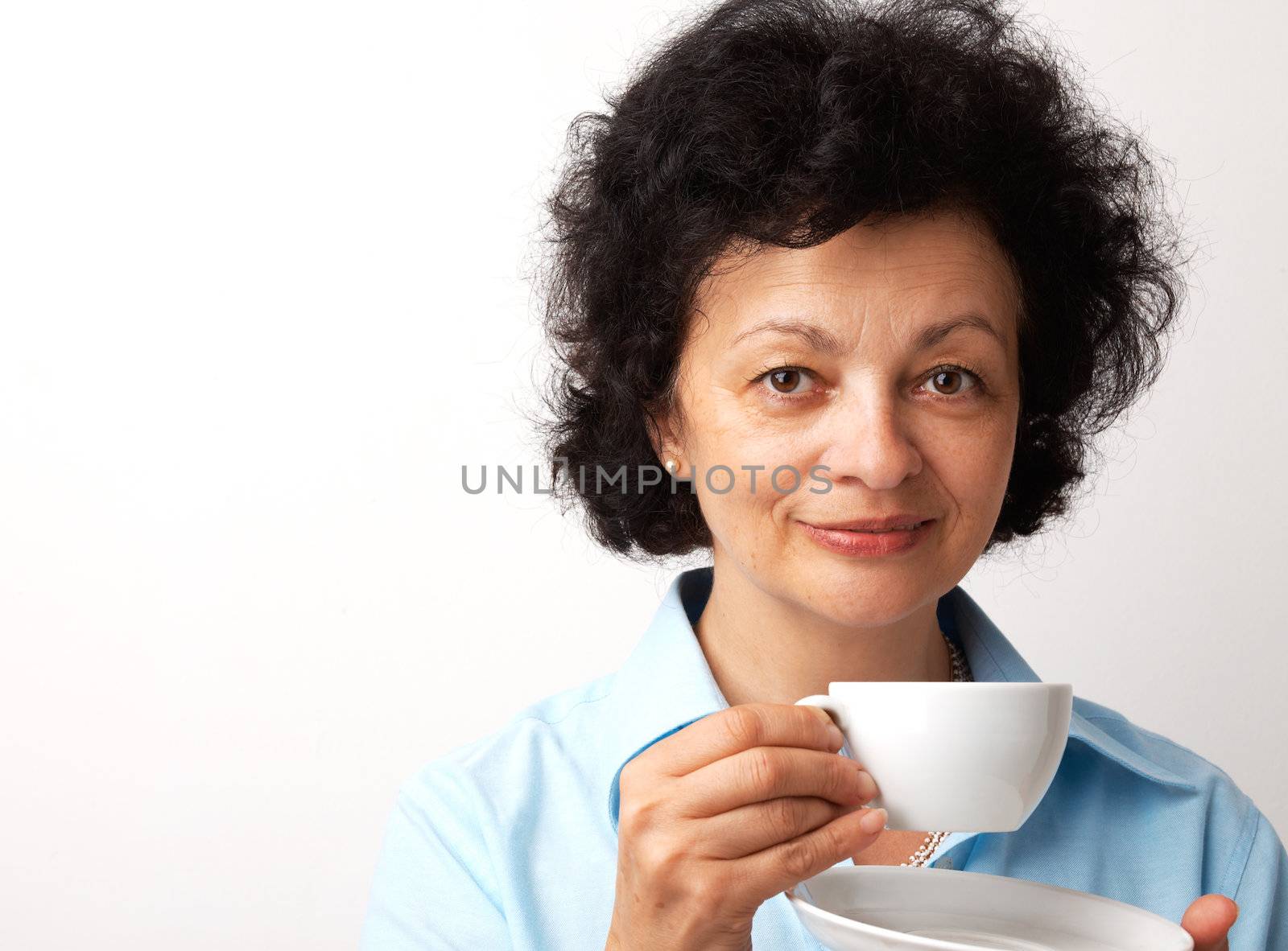 Close-up portrait of an elder smiling woman holding cup and saucer.