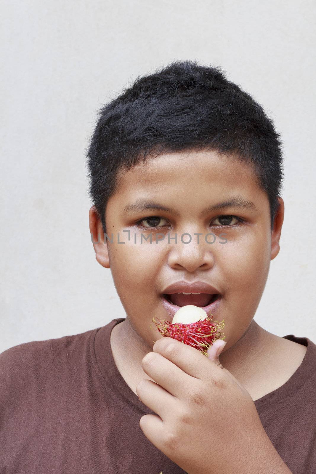 Thai teenage boy eating rambutan