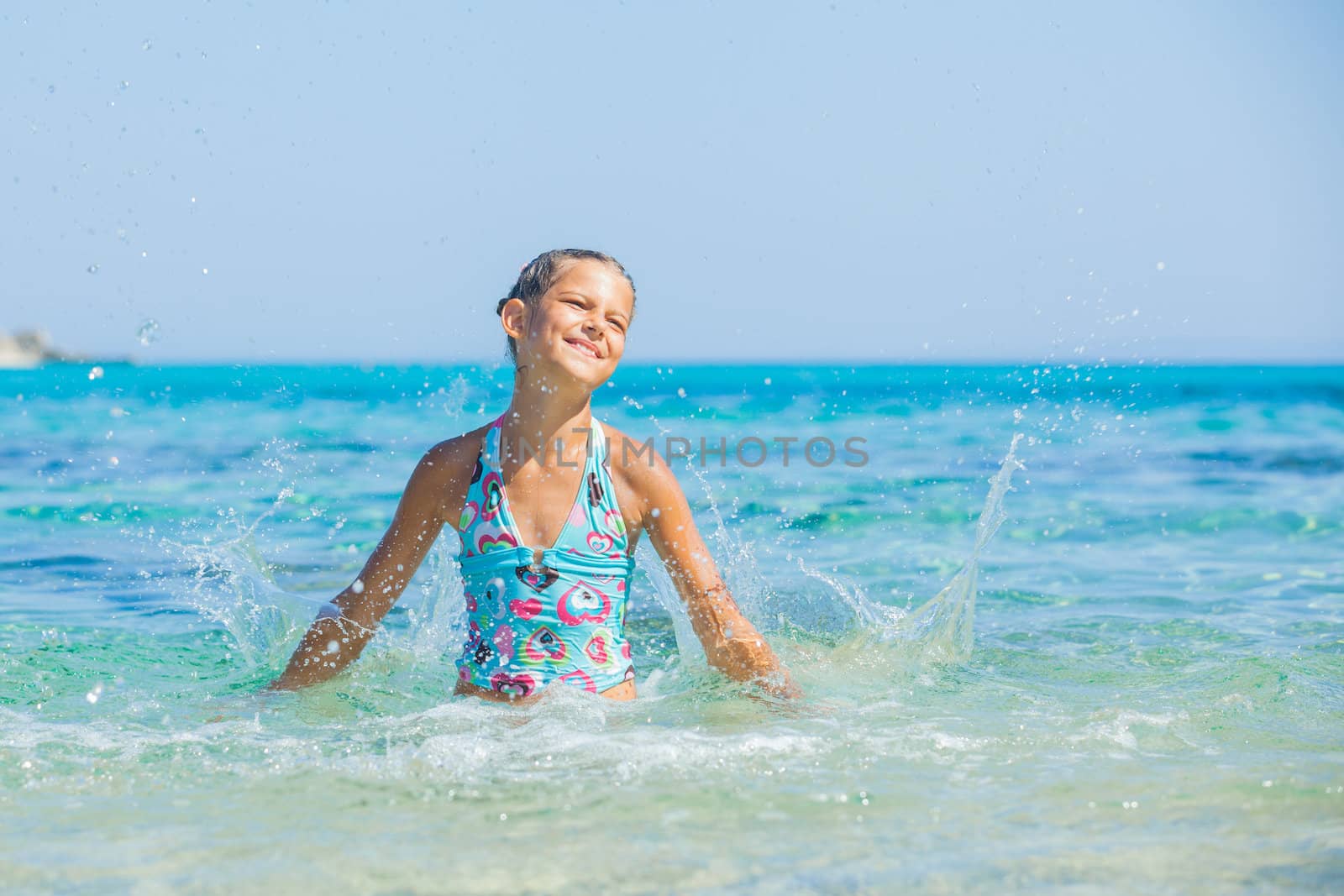 Young girl playing in the wave with spray