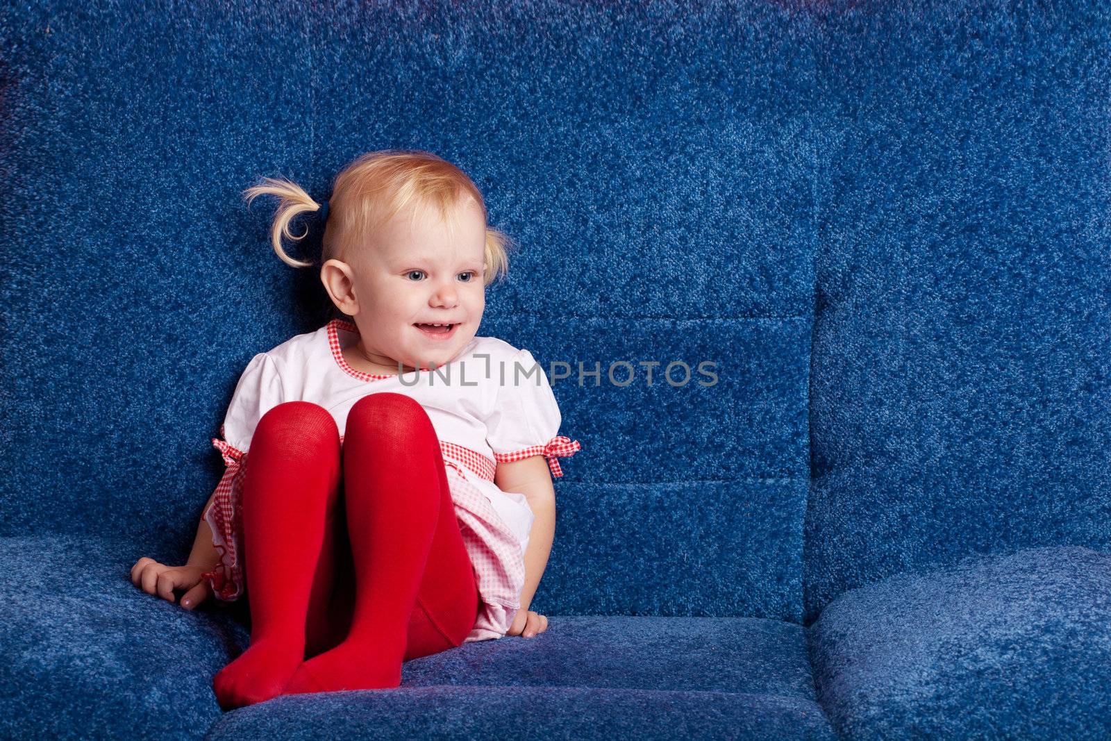 happy small girl sitting on the sofa