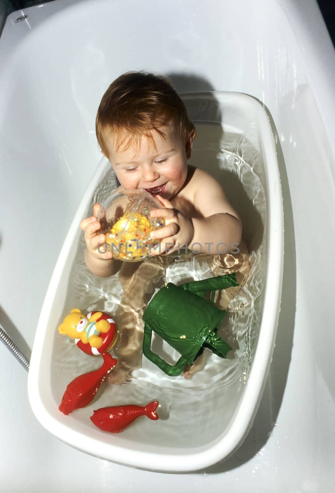 baby in the bath tube with his toys