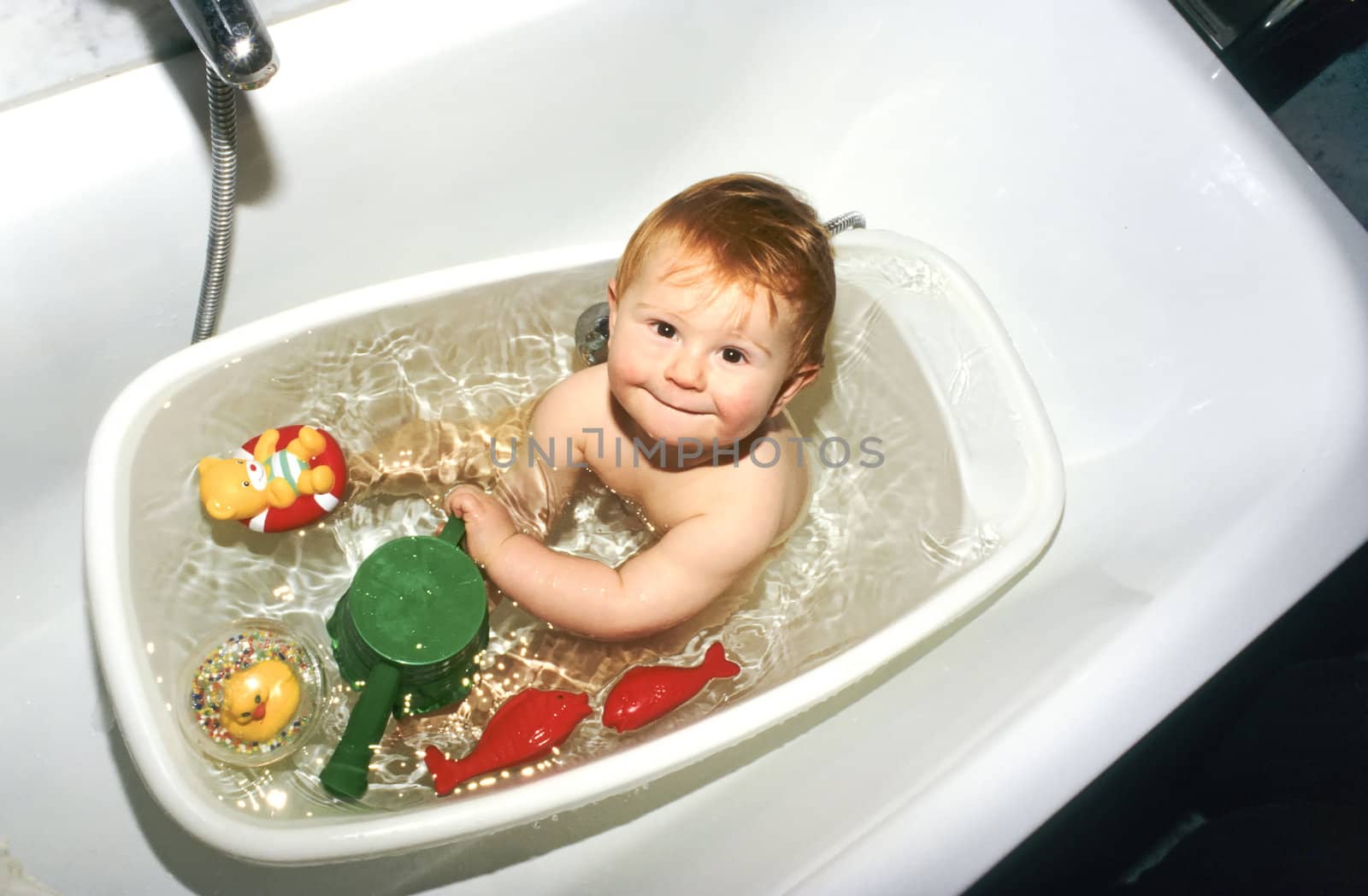 baby playing in bath with plastic toys