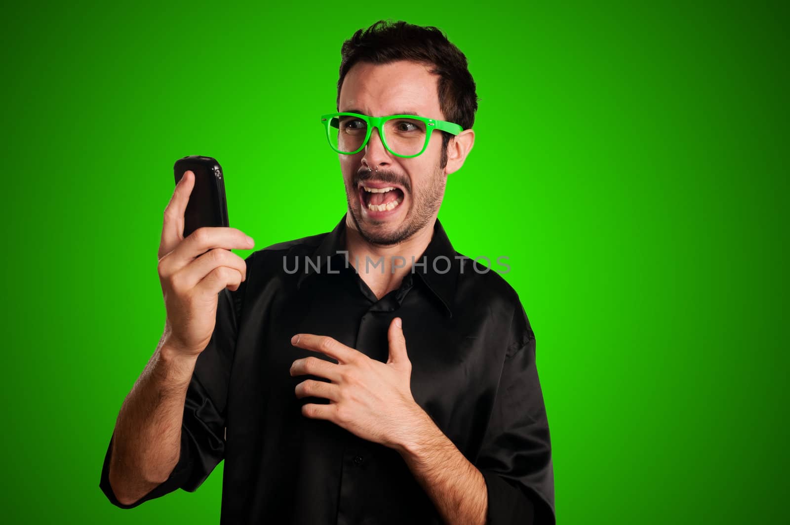 sared man holding phone on green background