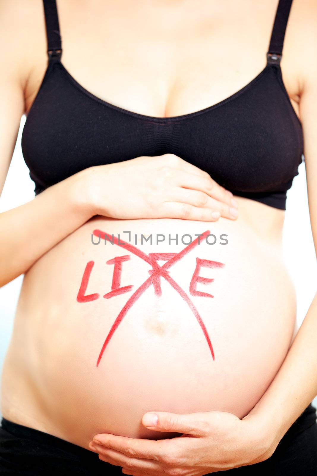 Pregnant lady showing her belly with Life written and crossed with marker on it.