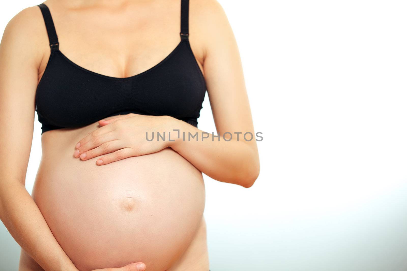 Pregnant woman cupping her belly in her hands by langstrup