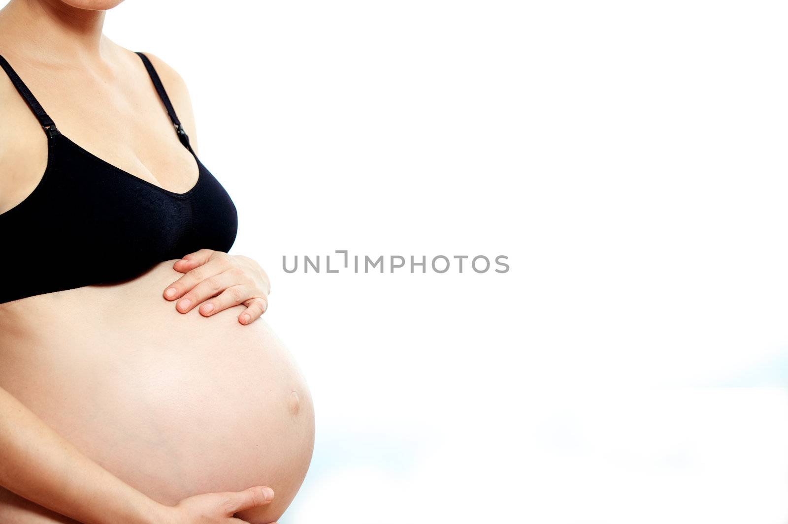 Sideways cropped portrait of a pregnant woman caressing her belly with her hands as she bonds with her unborn child isolated on white with copyspace